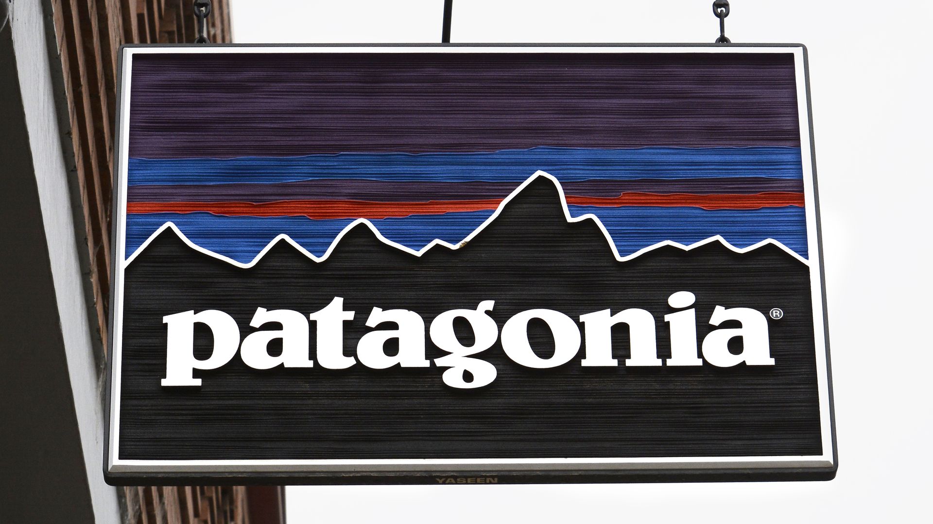 A small store advertising Patagonia, spelled out in white letters, hangs from the side of a building.