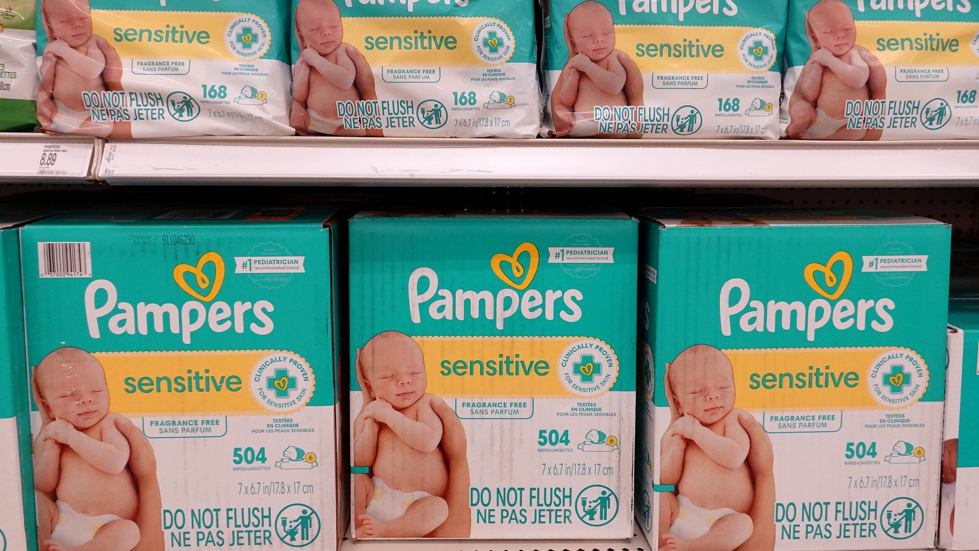 Teal Pampers Sensitive diaper packages on a store shelf, showing a baby and a yellow band labeled sensitive; includes a Do Not Flush icon.