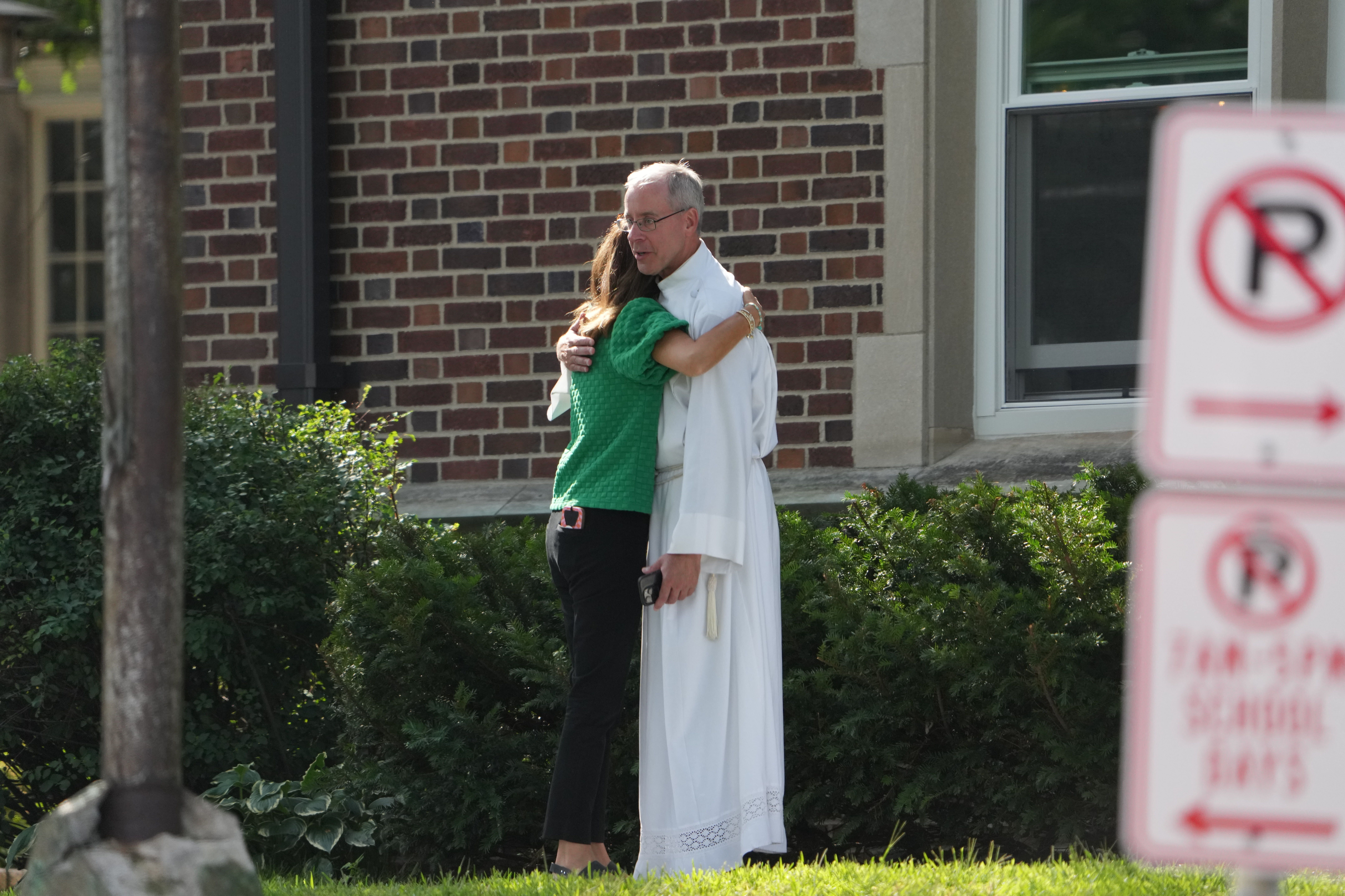 A clergyman comforts a woman outside Annunciation Catholic Church yesterday.