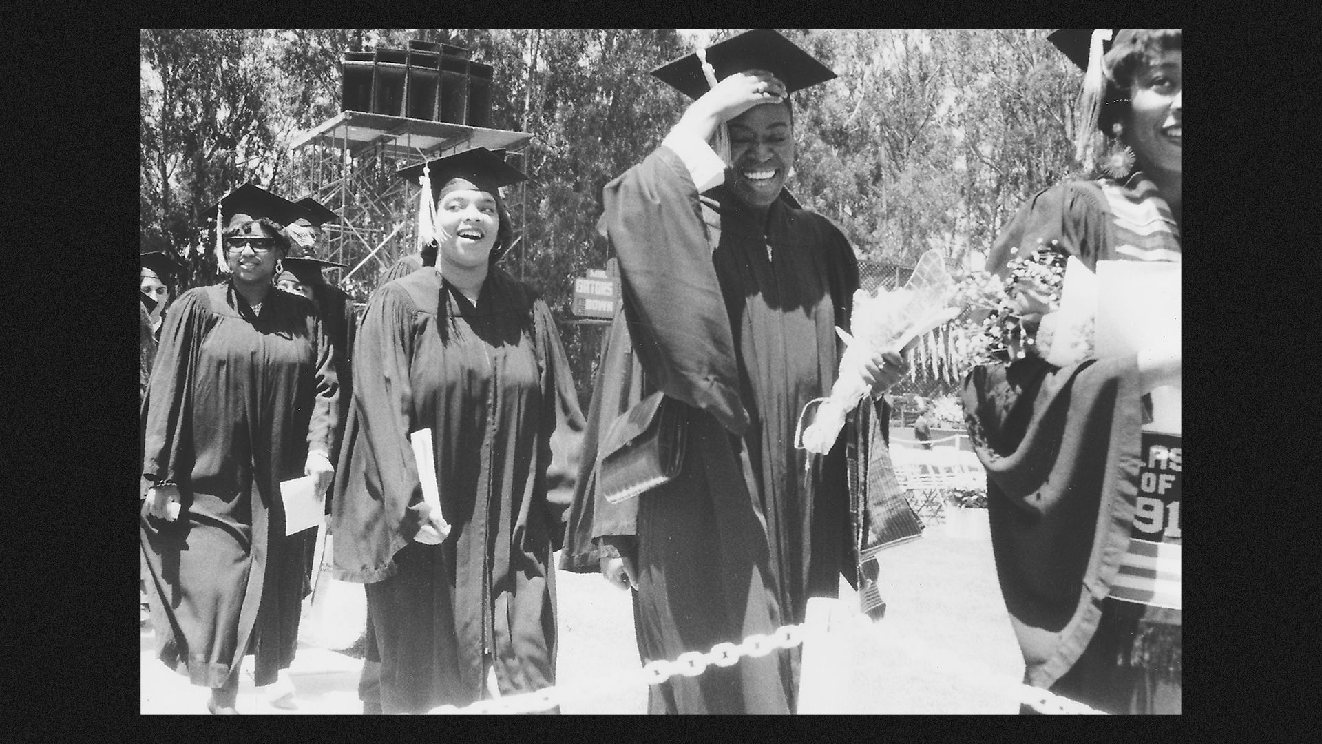 African-American college students wearing caps and gowns during a graduation ceremony.
