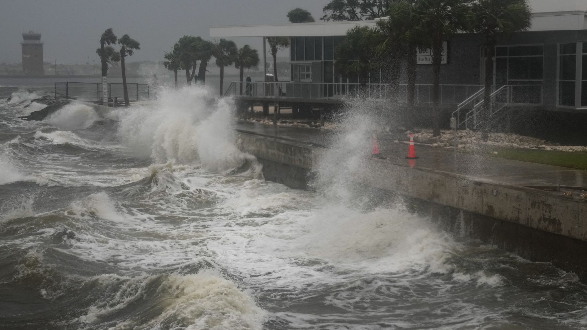 Tall waves hit a pier as a hurricane approaches the shoreline.