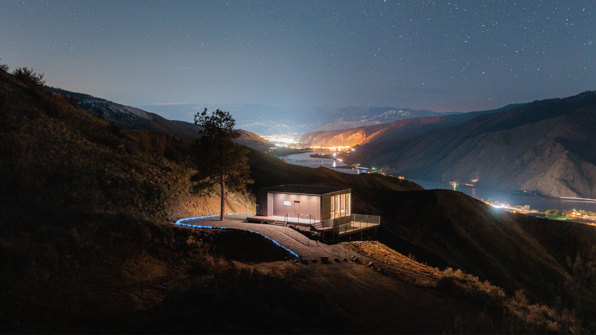 The Airbnb is shown at nighttime with stars above the ridge and the river spreading out below.