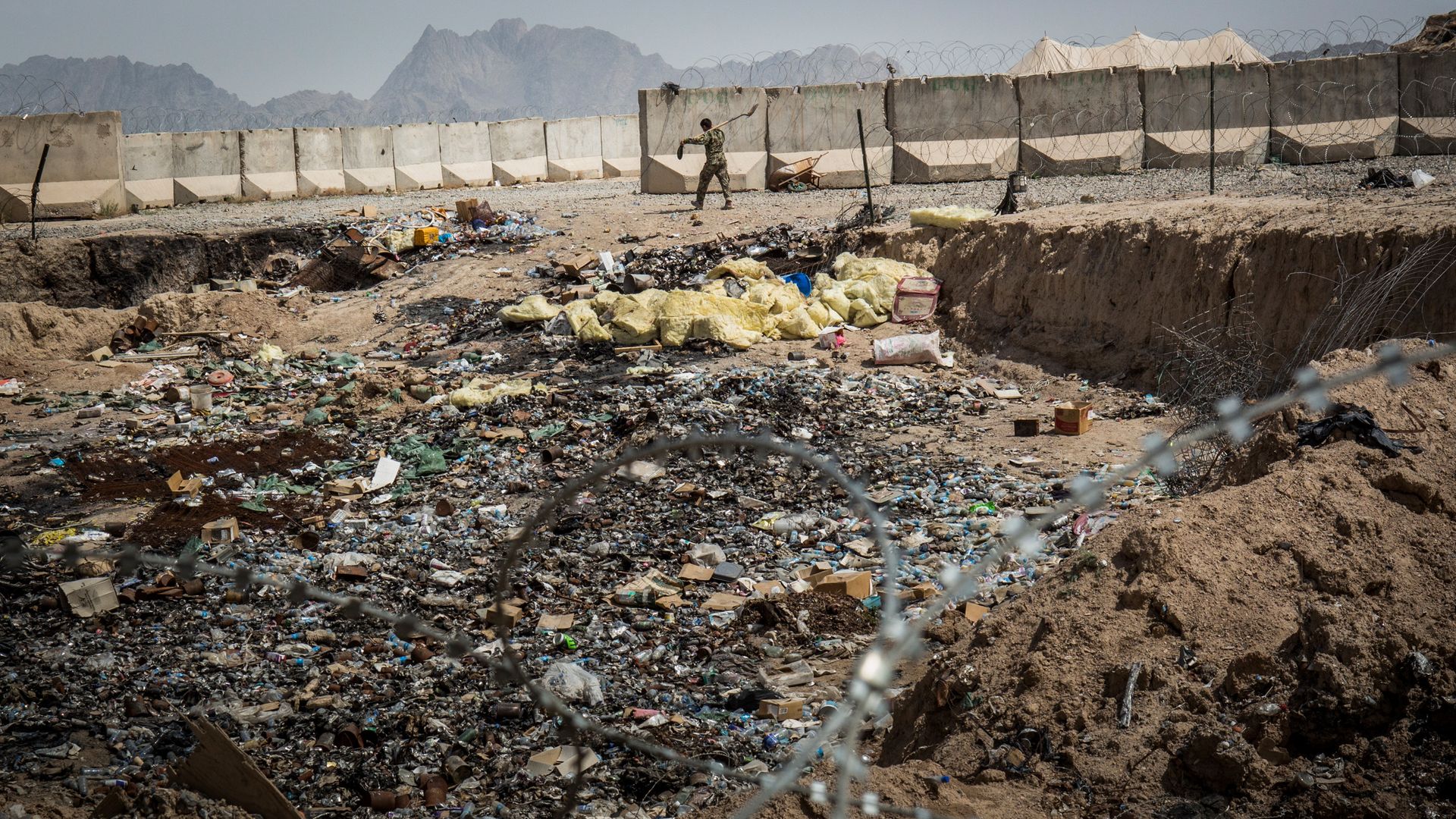A soldier in the Afghan National Army (ANA) walks past a burn pit at a command outpost.