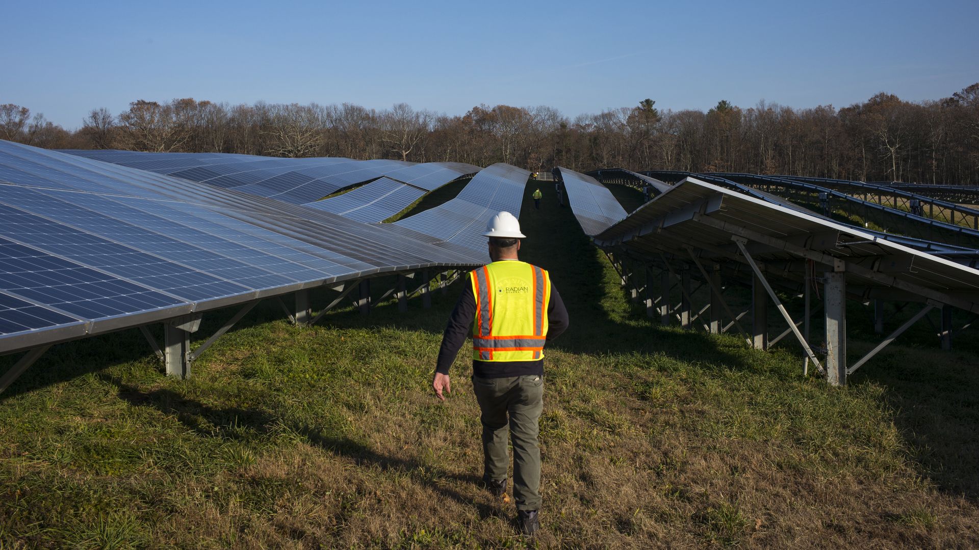 A man walks through a field with solar panels