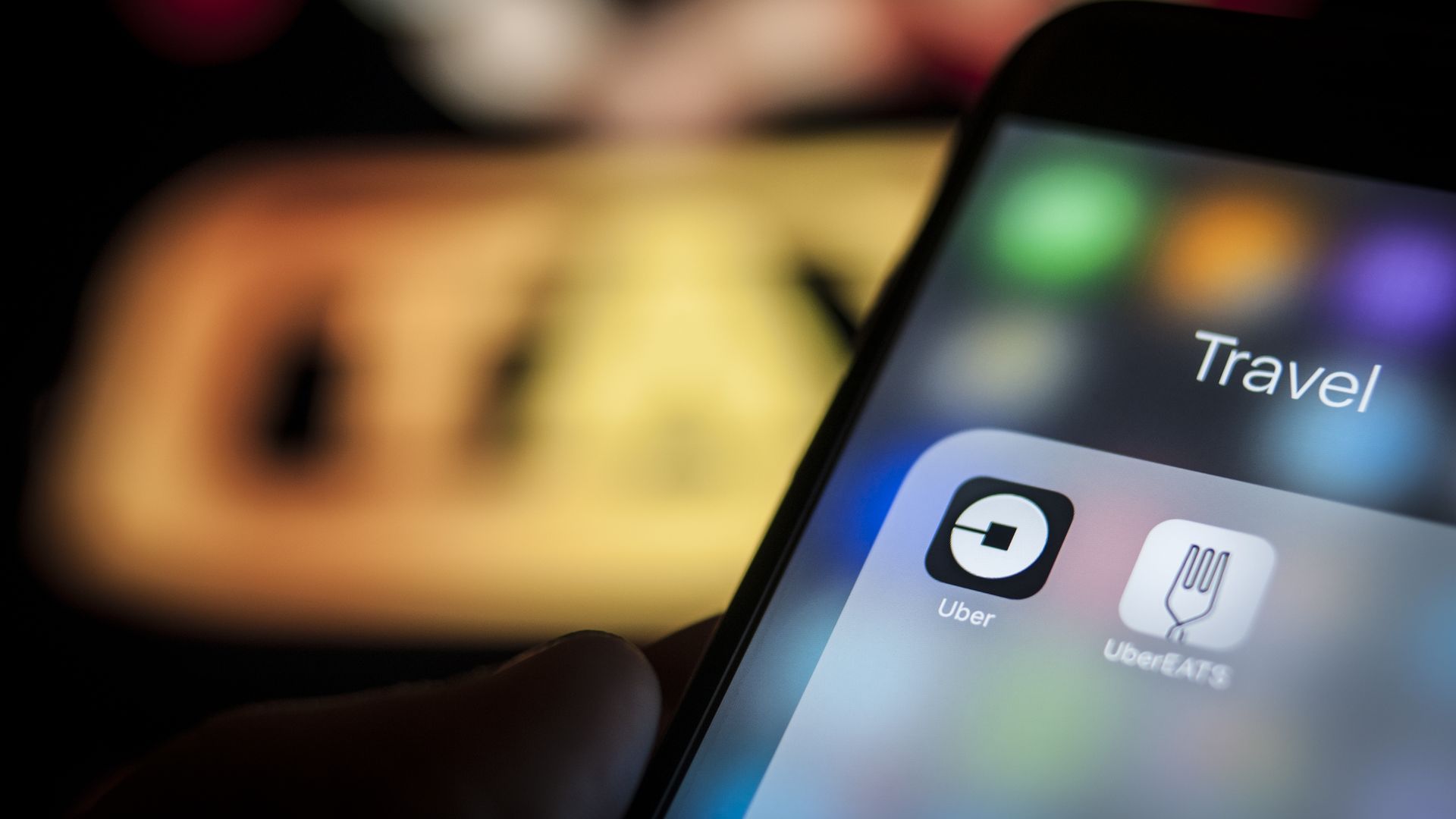 Phone with Uber and UberEats apps displayed.