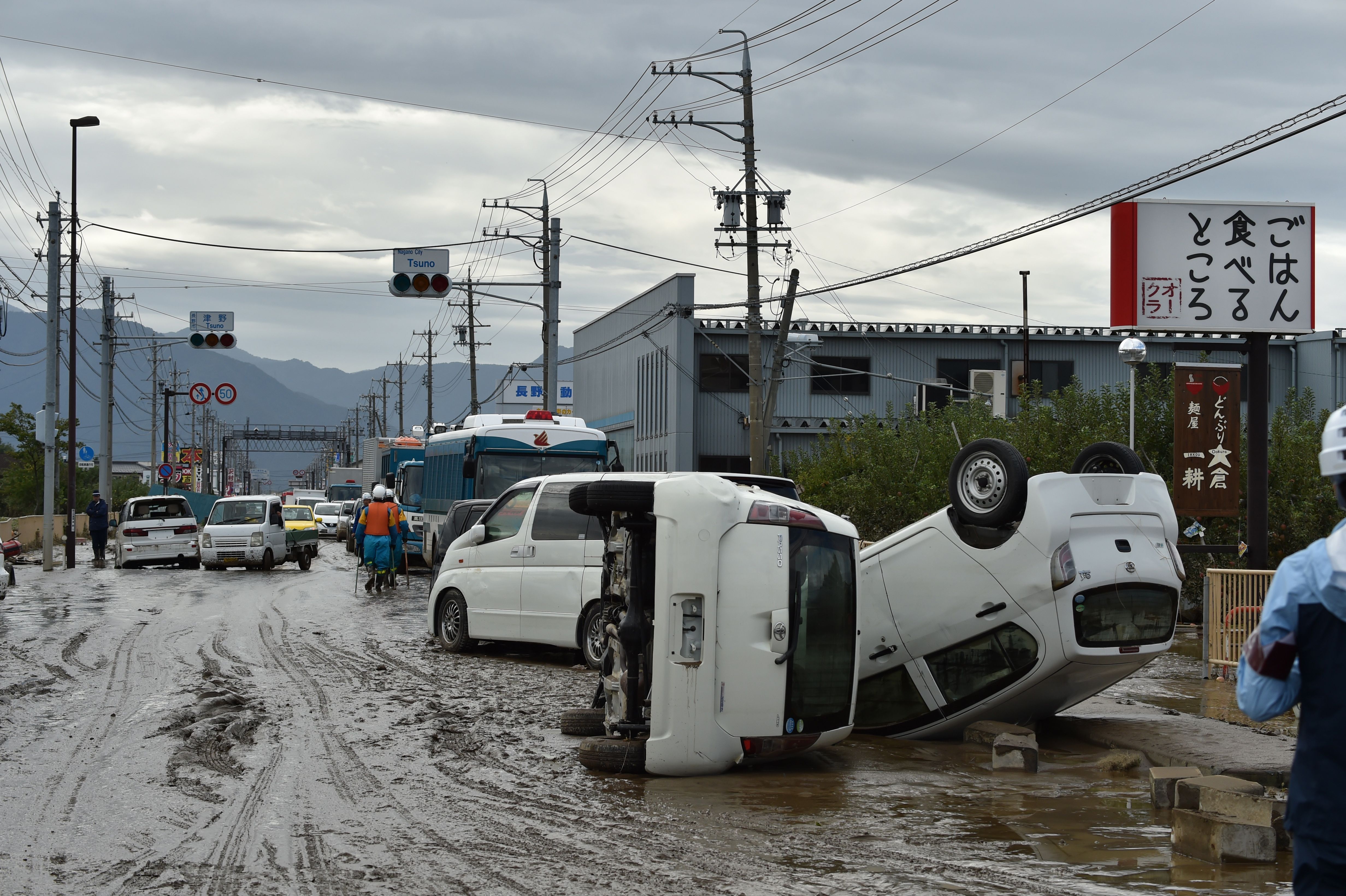 Overturned vehicles sit on the side of a muddy road in the aftermath of Typhoon Hagibis in Nagano 