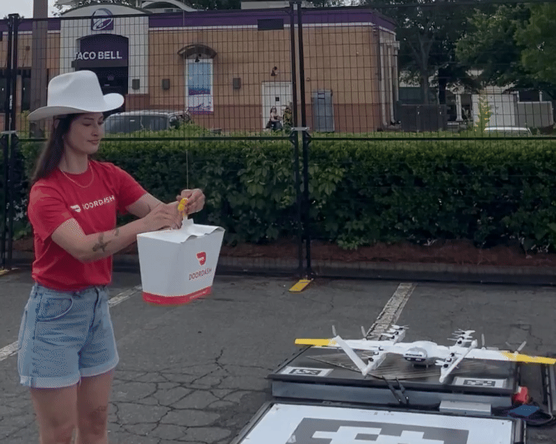 DoorDash worker attaches package to a drone