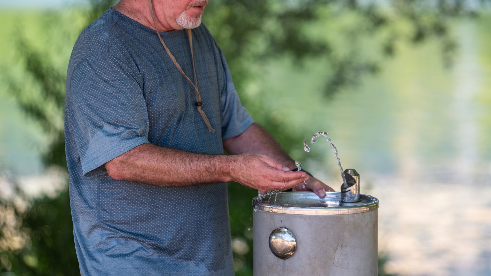 A photo of a man getting water out of a fountain.
