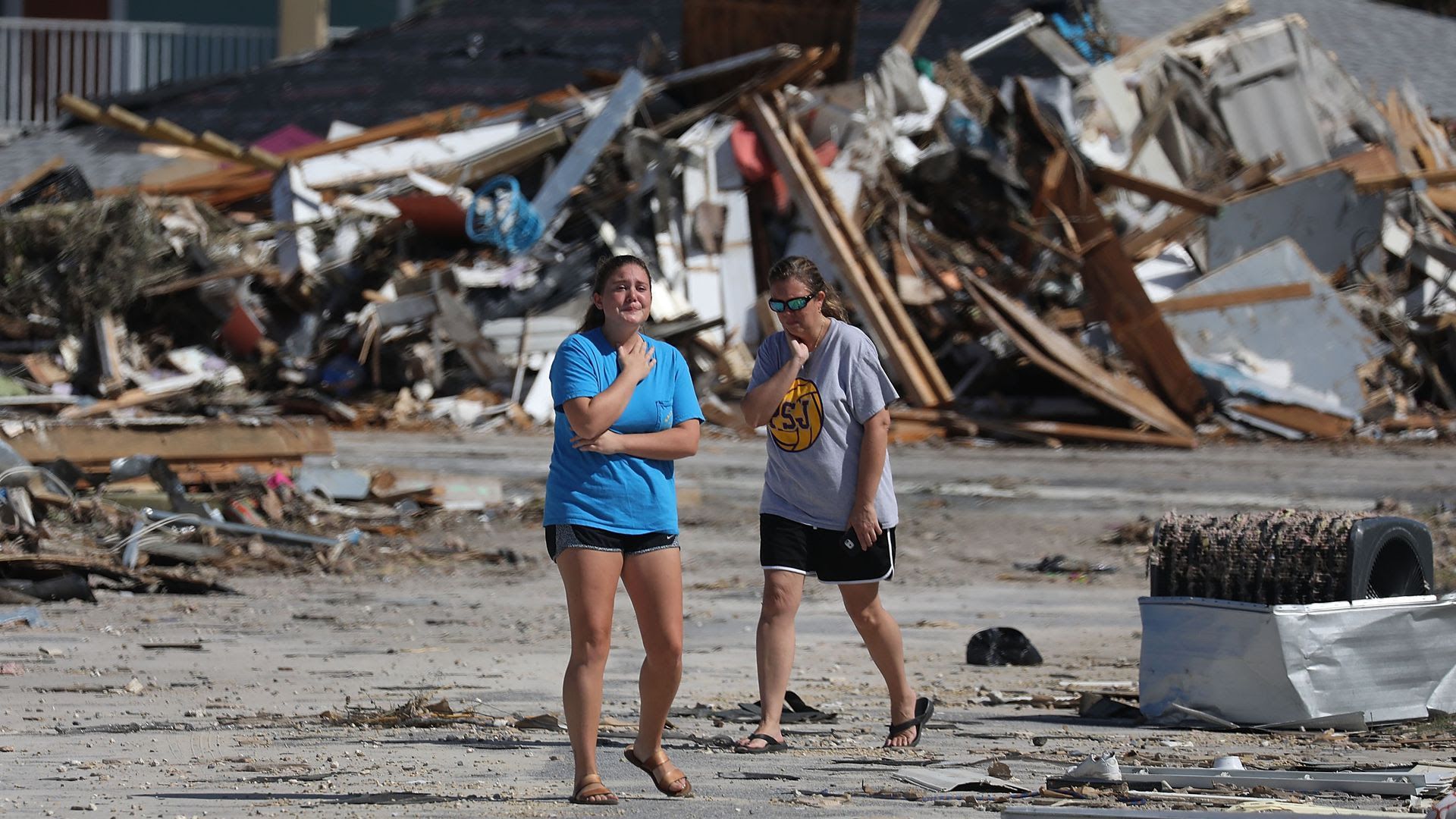 Two people stand among wreckage from Hurricane Michael.