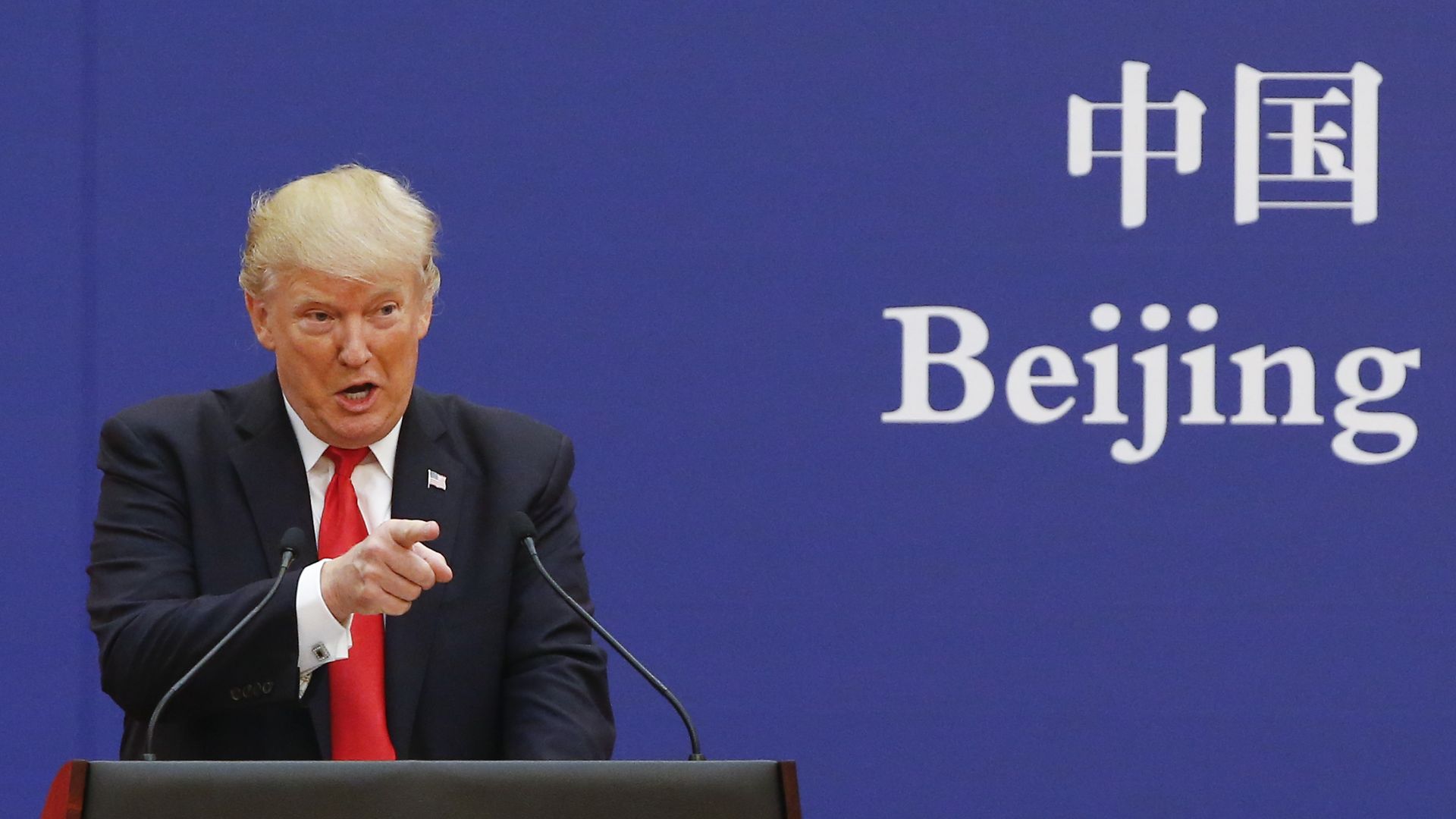 Trump speaks at a podium in Chine in front of a screen that says "Beijing"