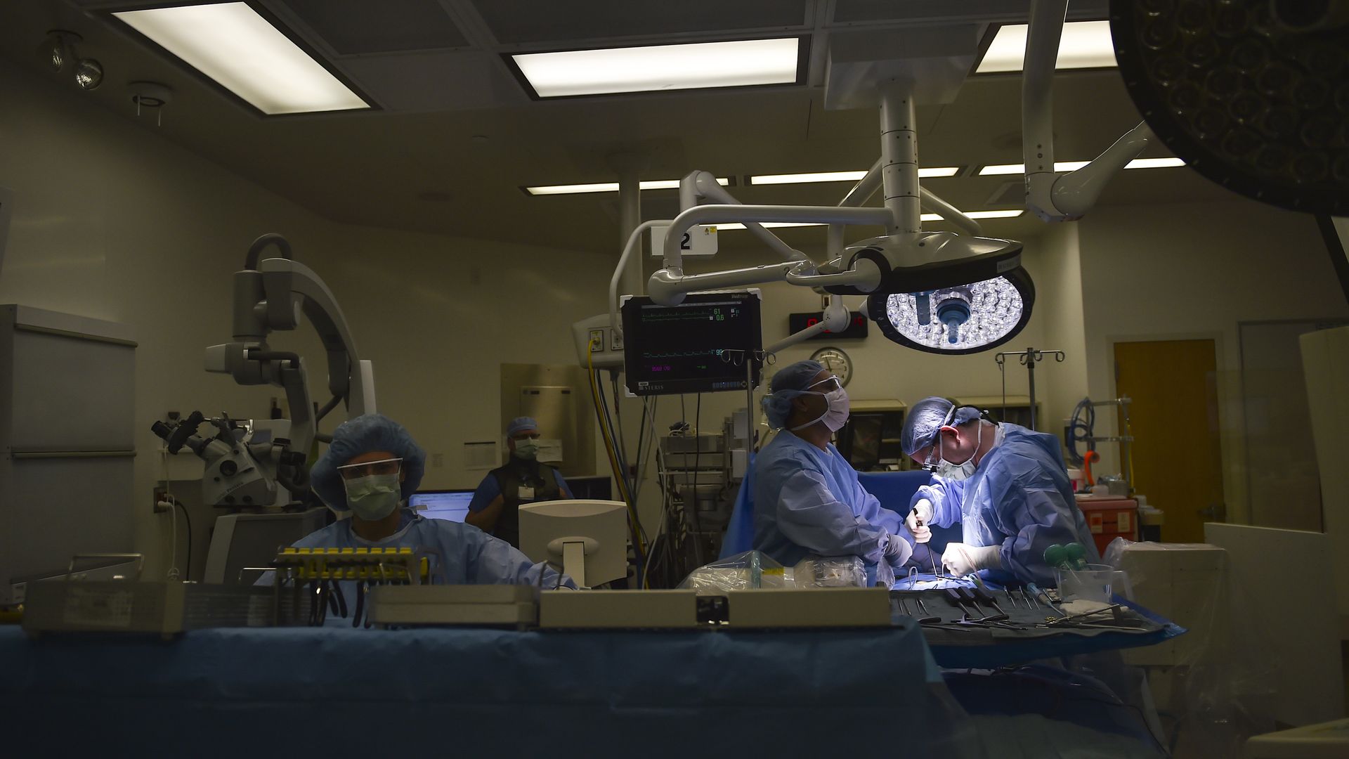 Surgeons work in a dimly lit operating room.