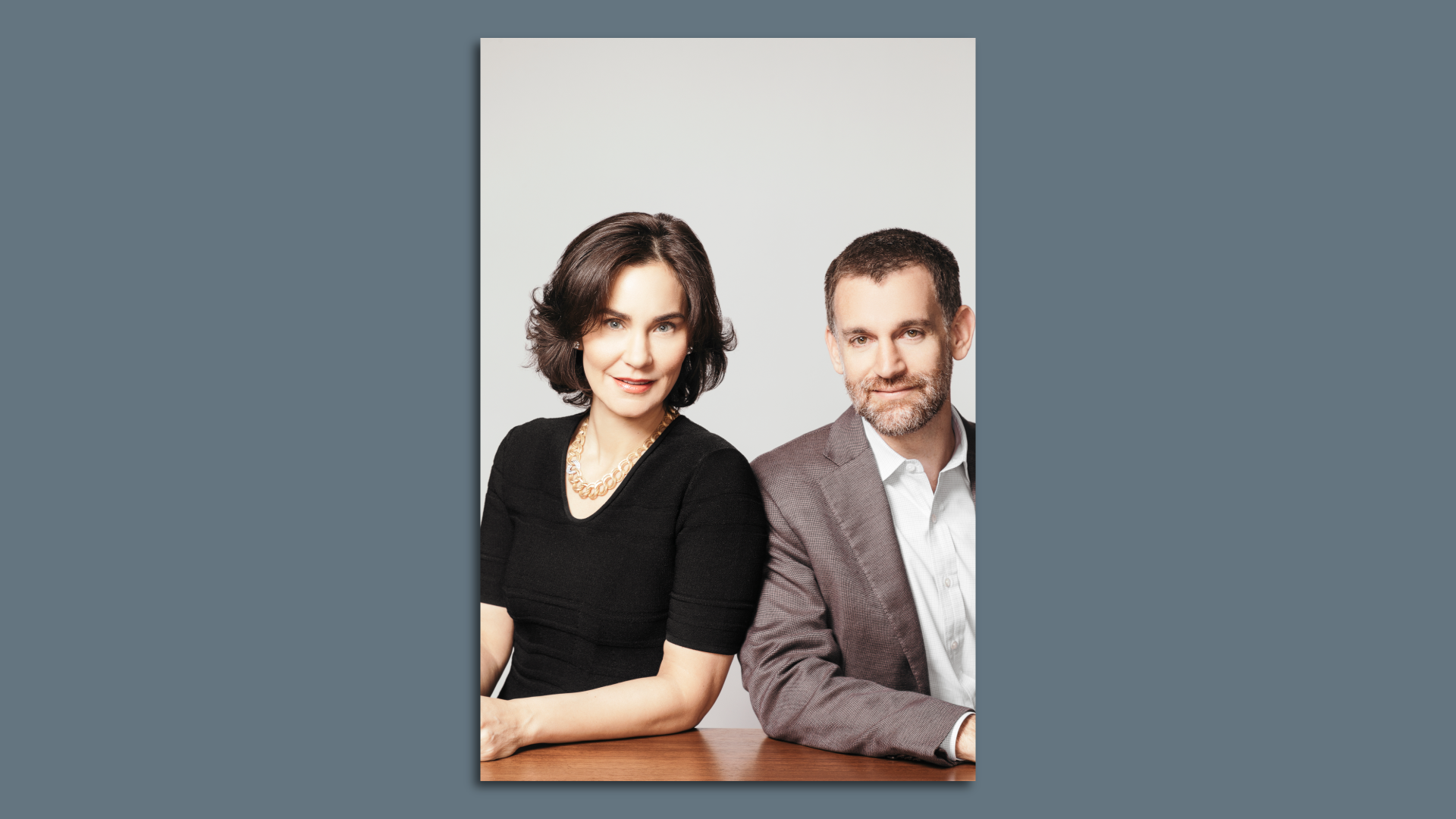 Laura and John Arnold pose for a photo while sitting at a desk