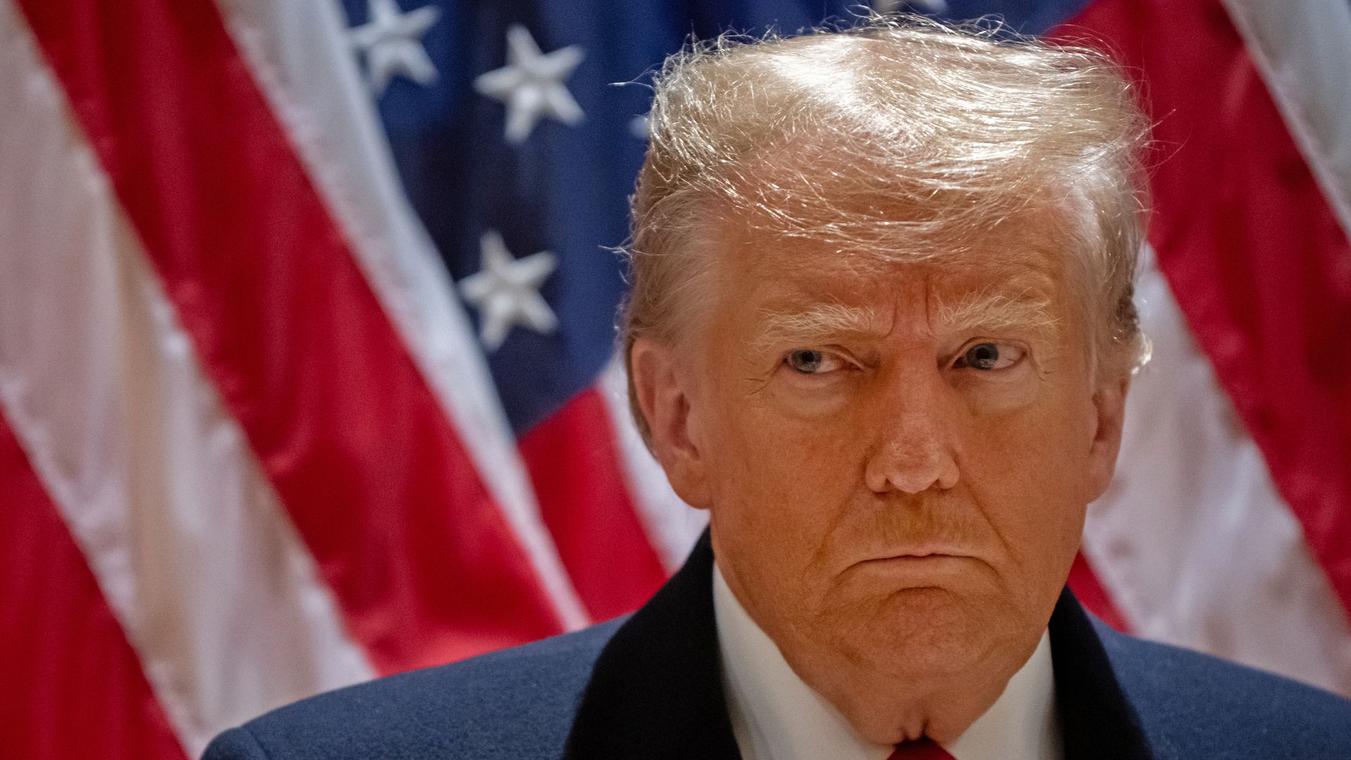 Donald Trump standing in front of an American flag