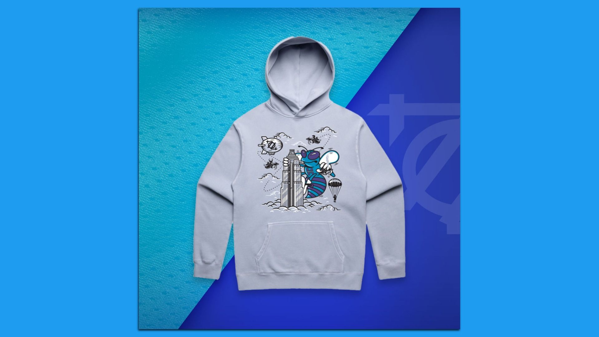 Light gray hoodie on a two-tone blue background with diagonal panels. The front shows a tall skyscraper and a blue striped insect with white wings, clouds, a hot air balloon, and small aircraft.