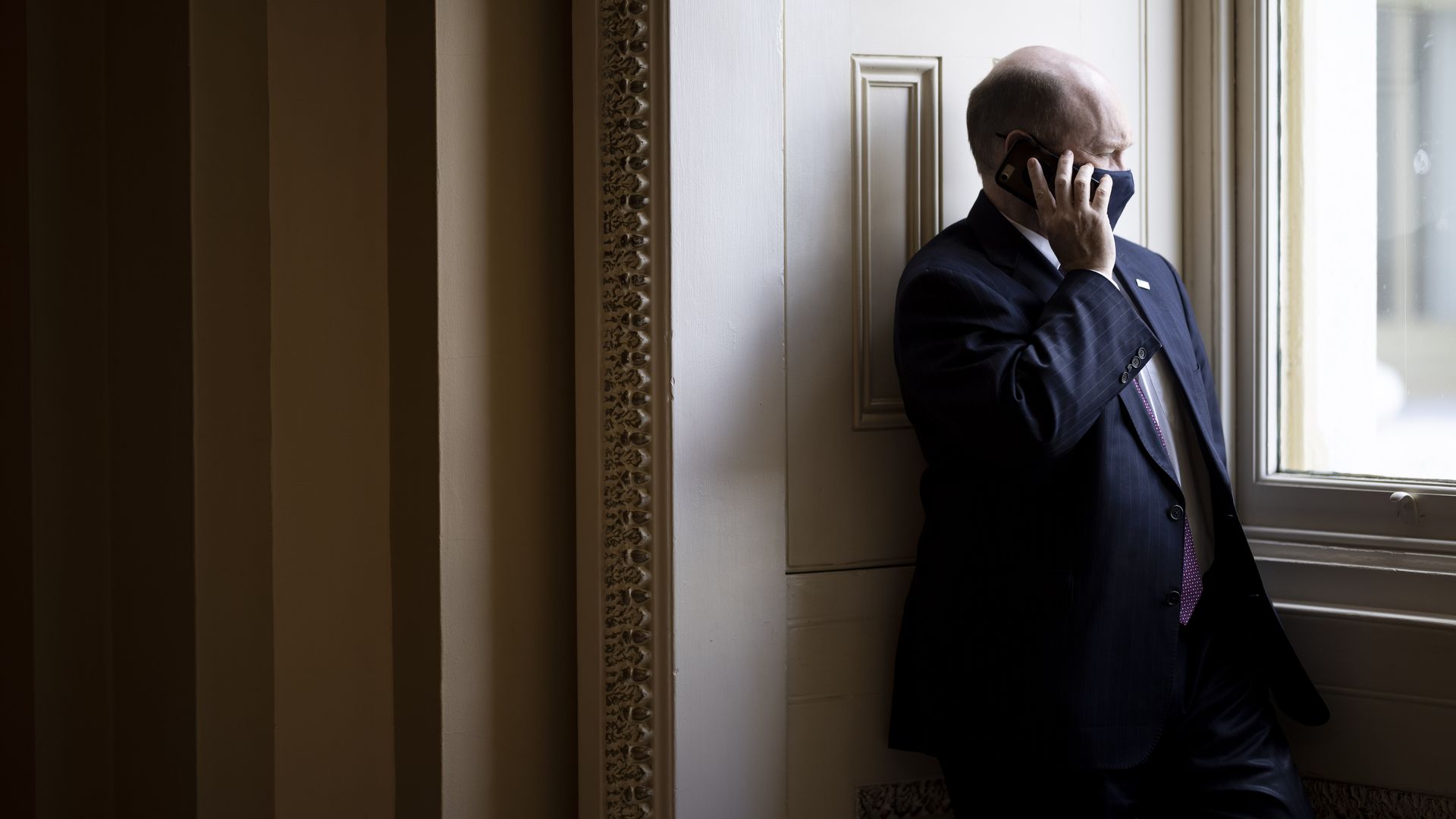 Sen. Chris Coons is seen looking out a window in the Capitol.