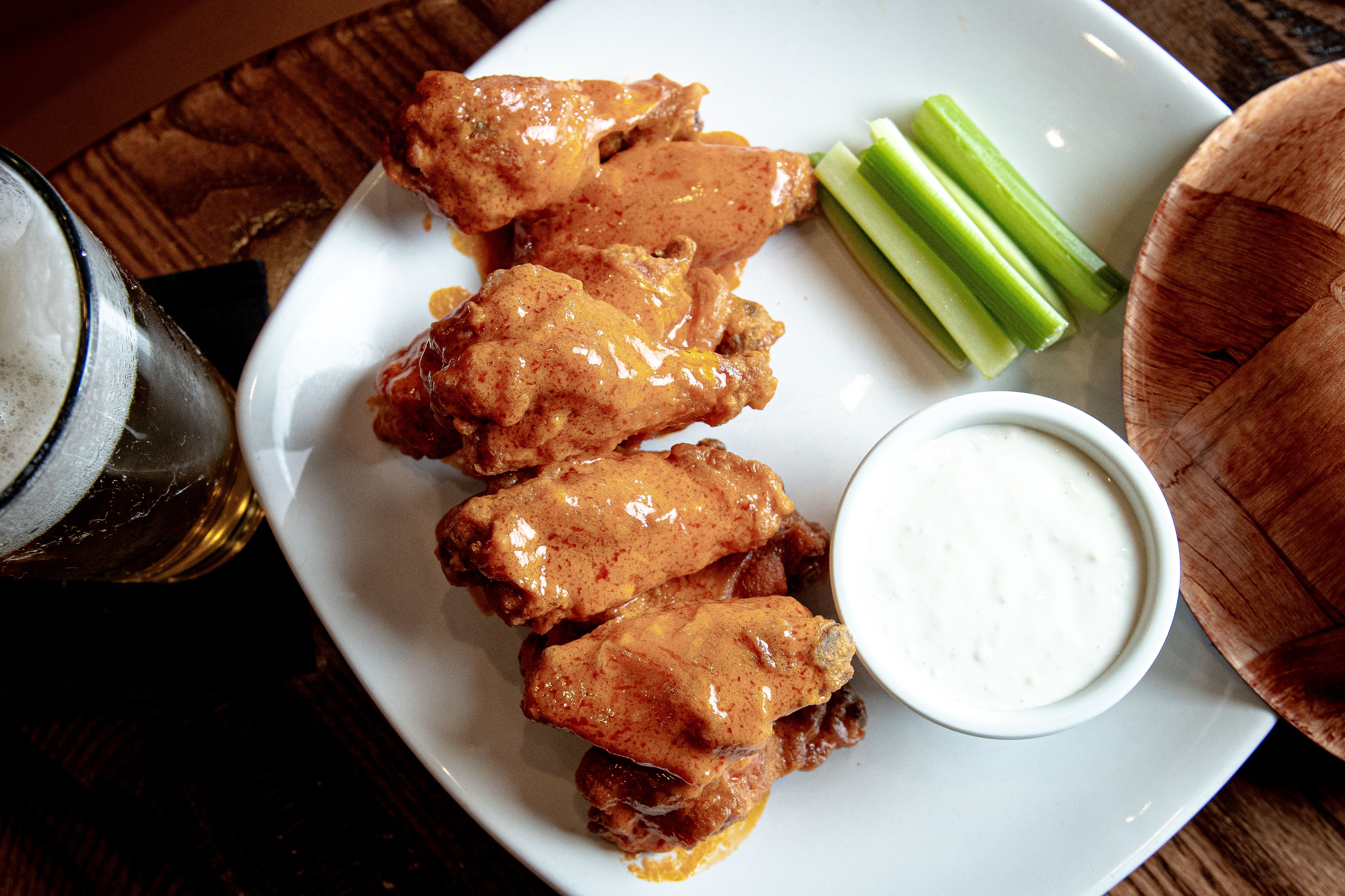 Buffalo wings on a white plate with sauce and celery