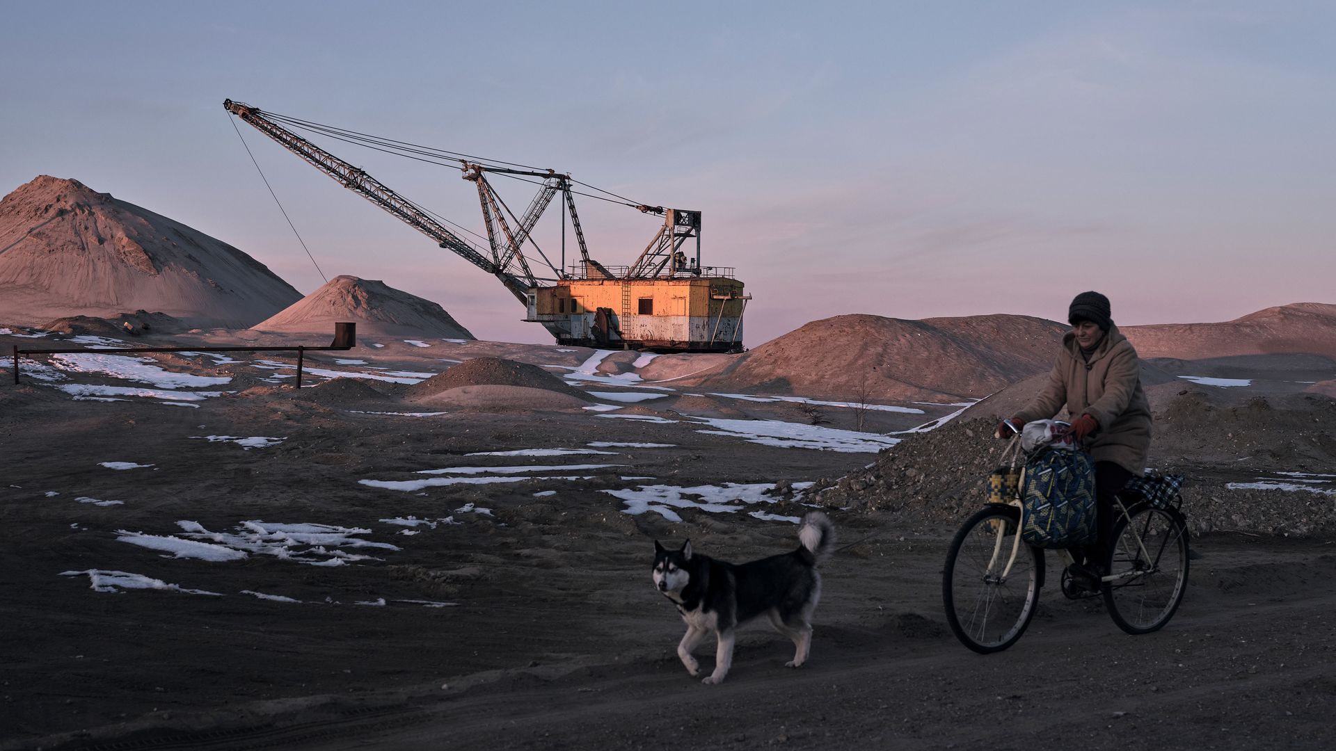 A woman cycles past with her dog as bucket-wheel excavators mine rare earth materials on Ukrainian soil on February 25, 2025 in the Zhytomyr region of Ukraine.