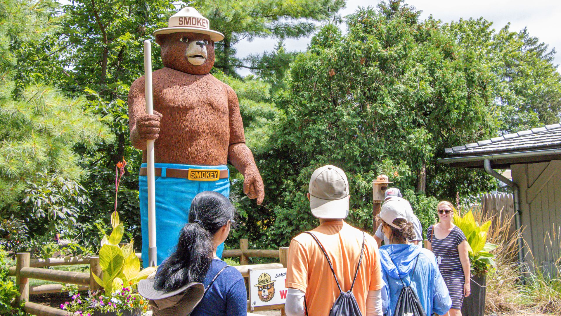 A crowd looks at a large Smokey Bear statue