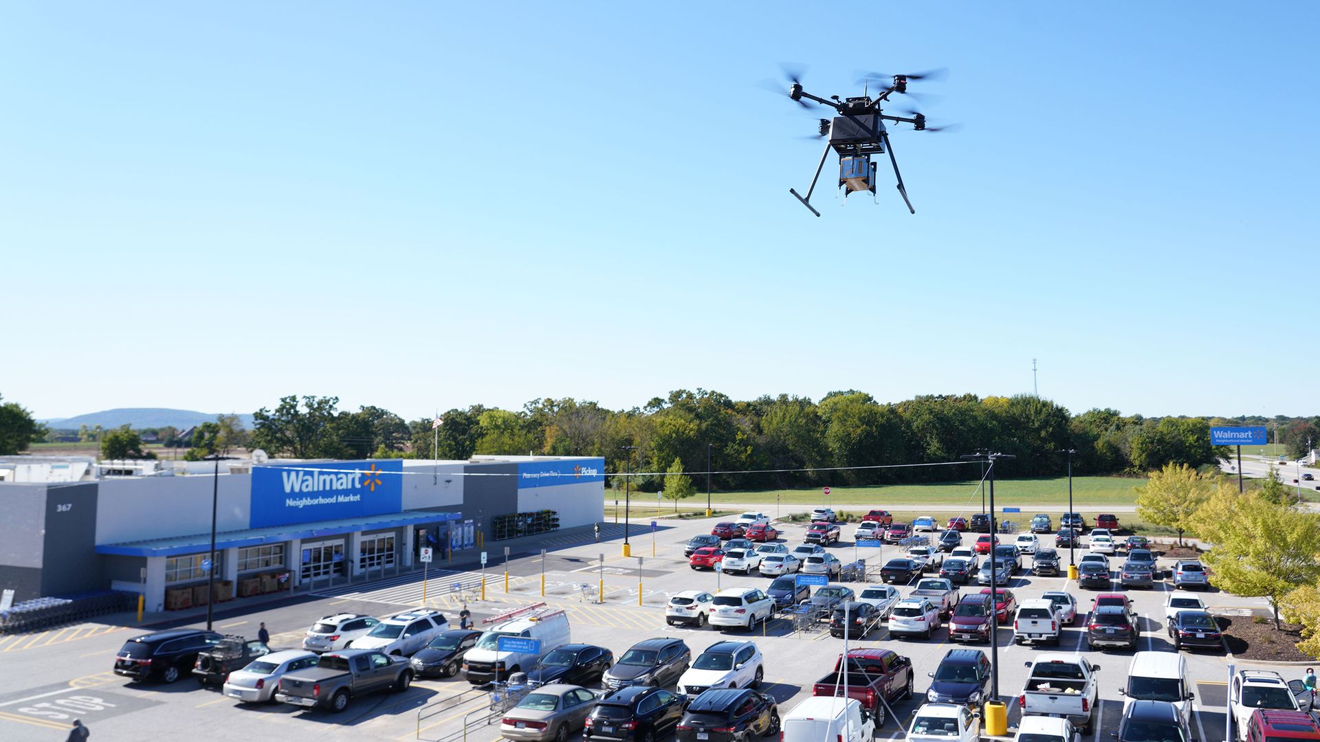 A Walmart drone flies over a parking lot.