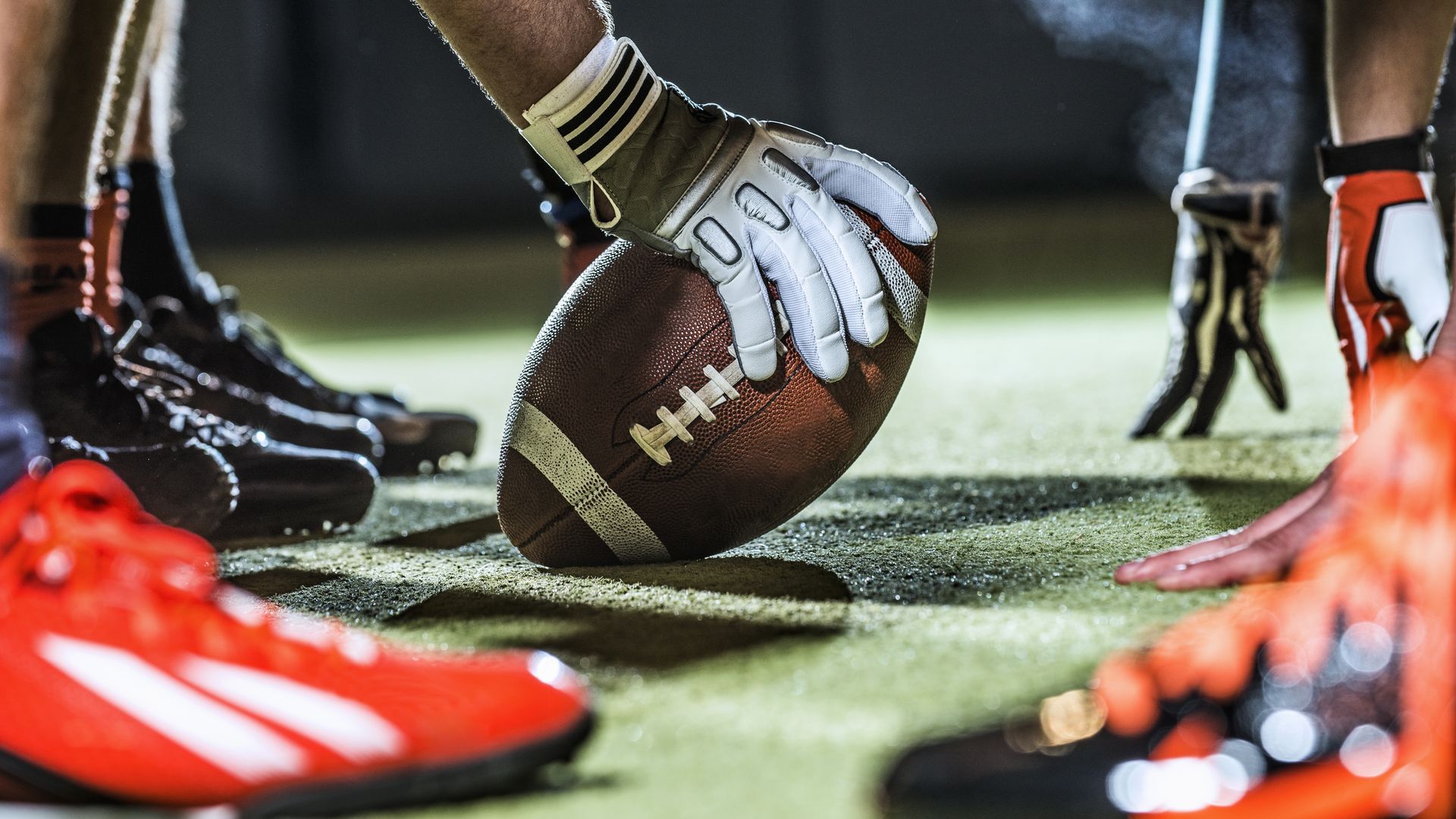 A football player with a football on a field getting ready to play