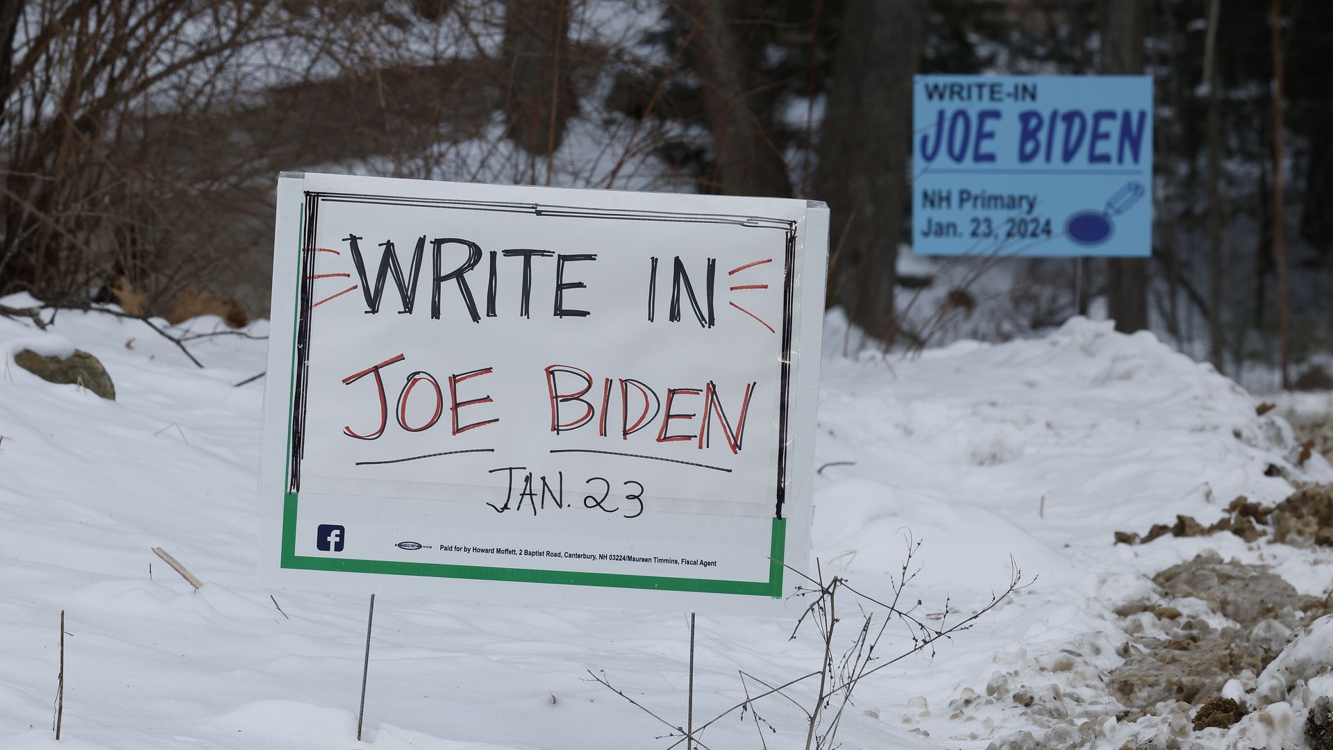 A sign says "Write in Joe Biden Jan. 23" on snowy ground 