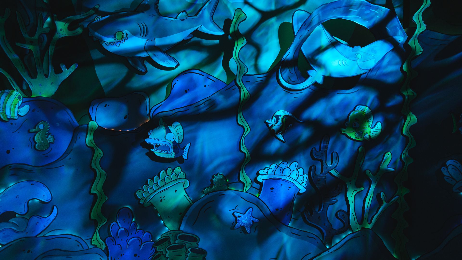 Cartoon characters of marine animals are seen on a wall with rippling shadows.