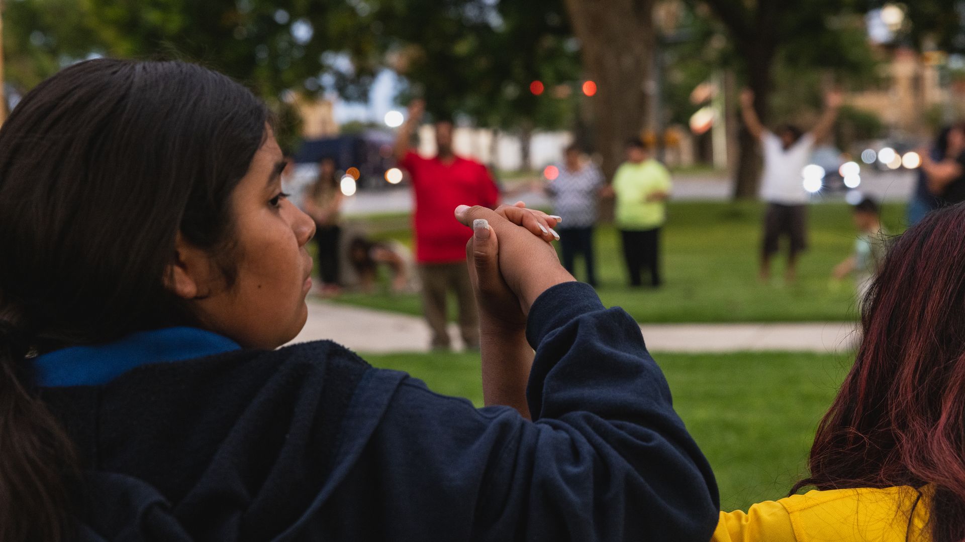 A girl is seen holding hands with another person while they are in a circle prayer group in Uvalde, Texas