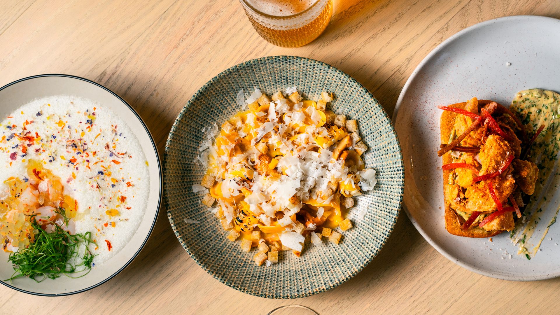 A view from above shows three dishes on a light wood table. Clementine's featured dishes for the San Antonio Food Bank Restaurant Weeks are, from left to right: chilled canary melon and champagne soup, corn tortellini and fried green tomatoes.