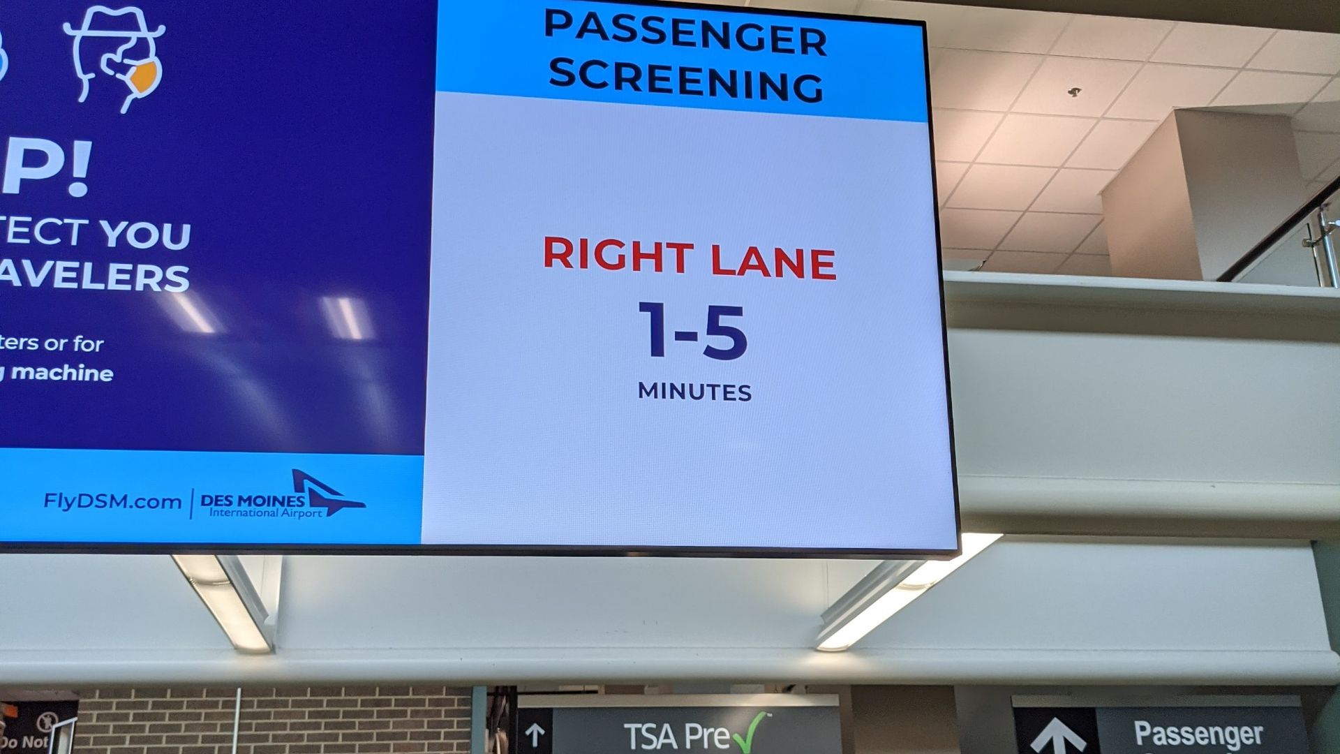 A screen at the DSM airport showing a 1-5 minute wait