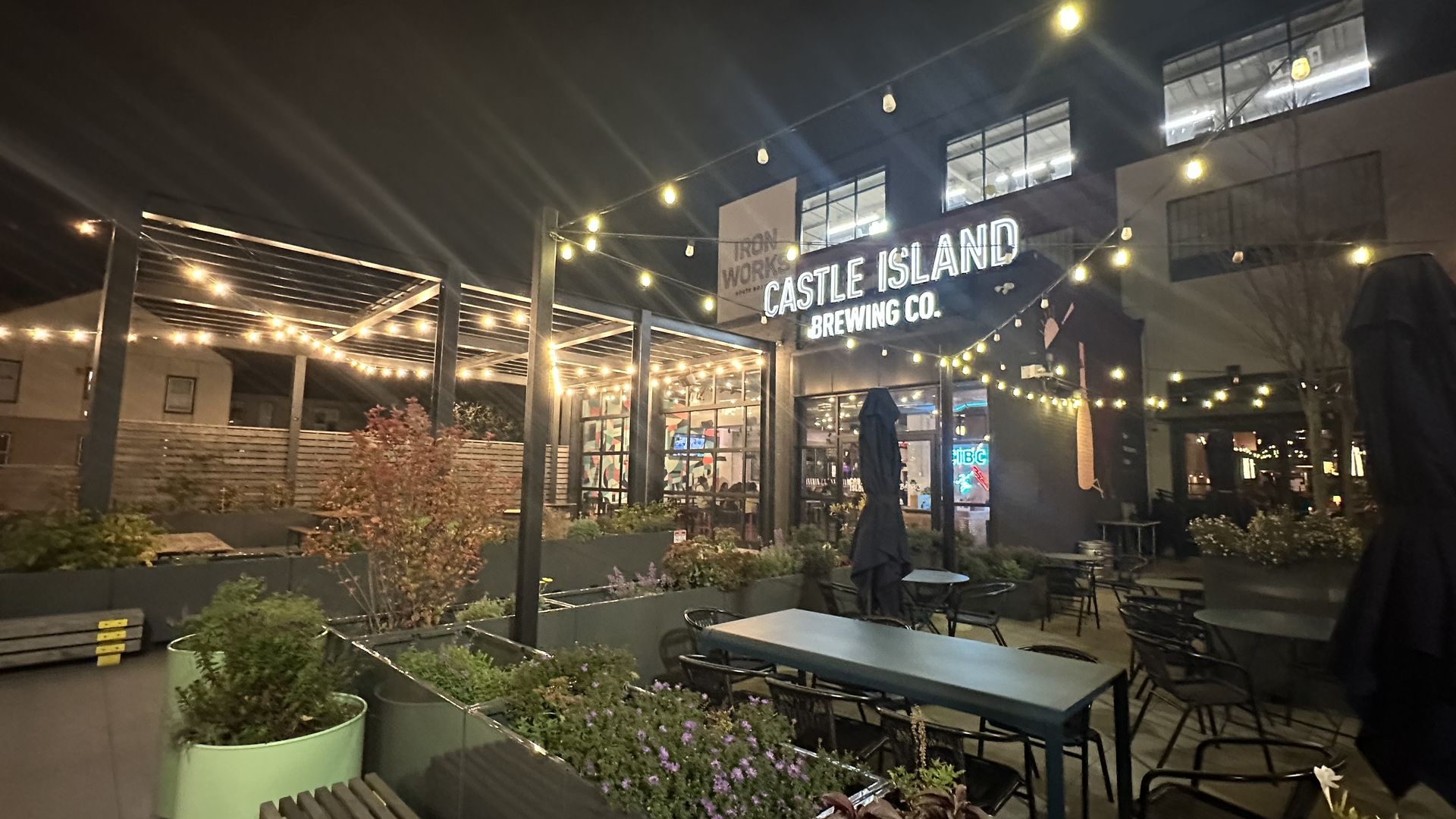 Outdoor seating at the entrance to Castle Island Brewing in South Boston at night. 