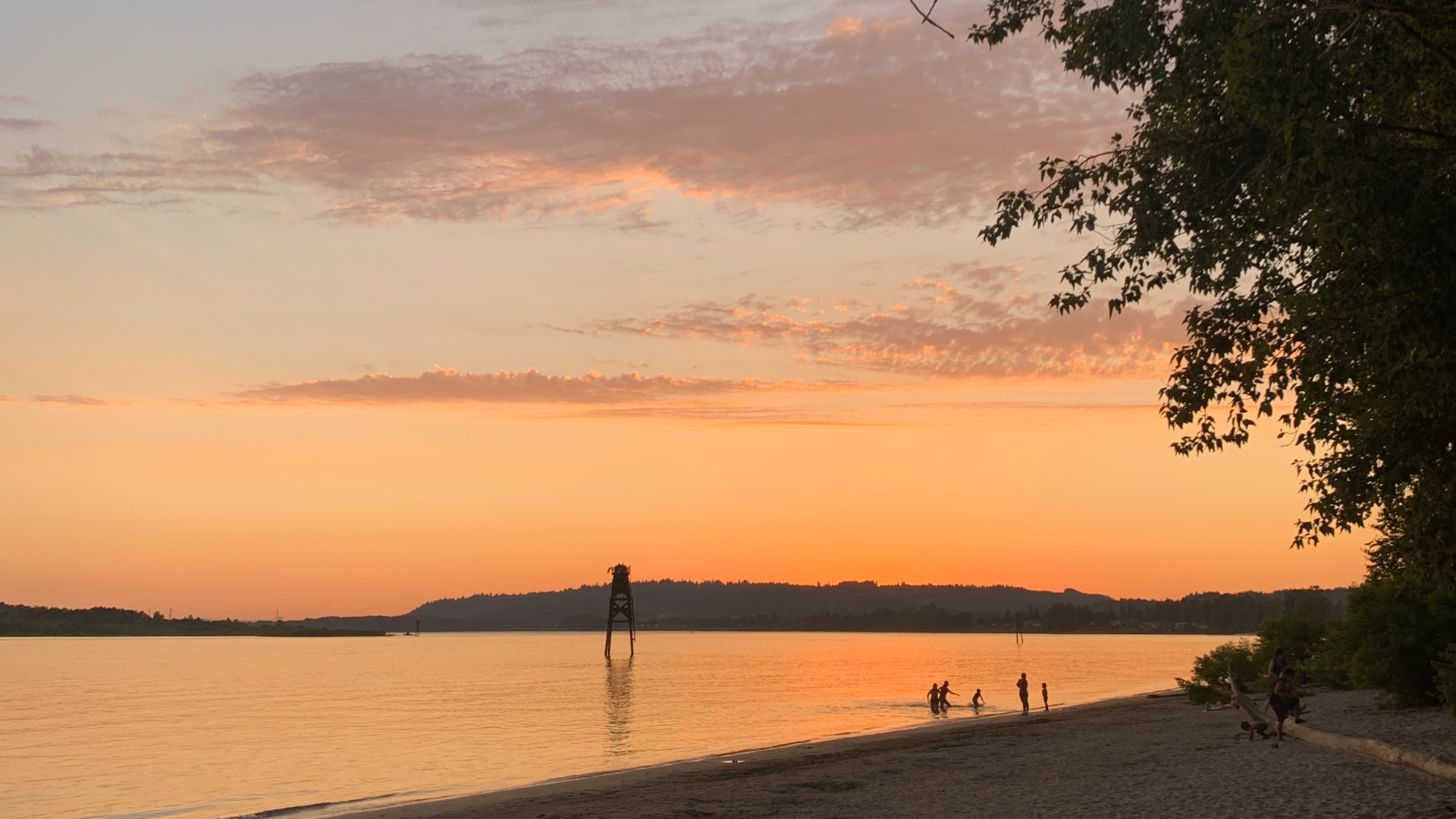 A photo of people playing in a river at sunset.