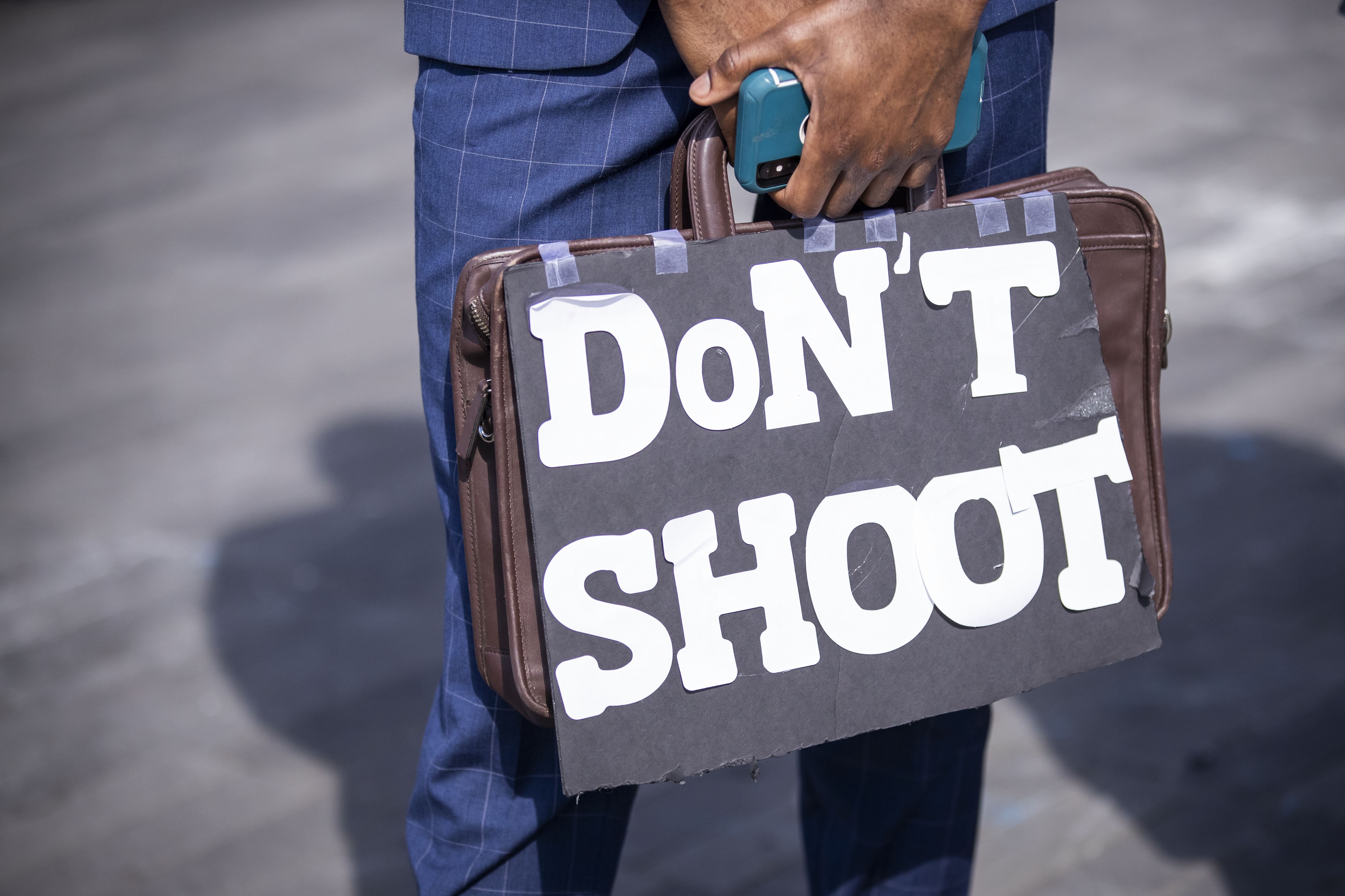 Illustration of a protester holding a suitcase that says "Don't shoot"