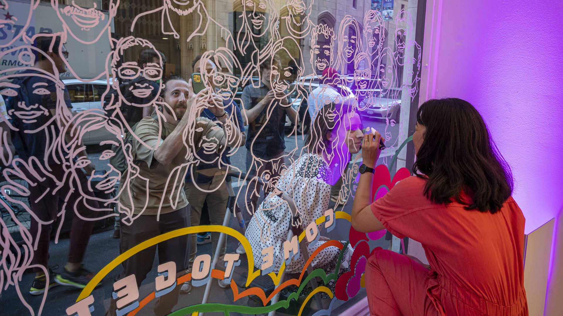 Photo of a person drawing caricatures on a window outside a radio event