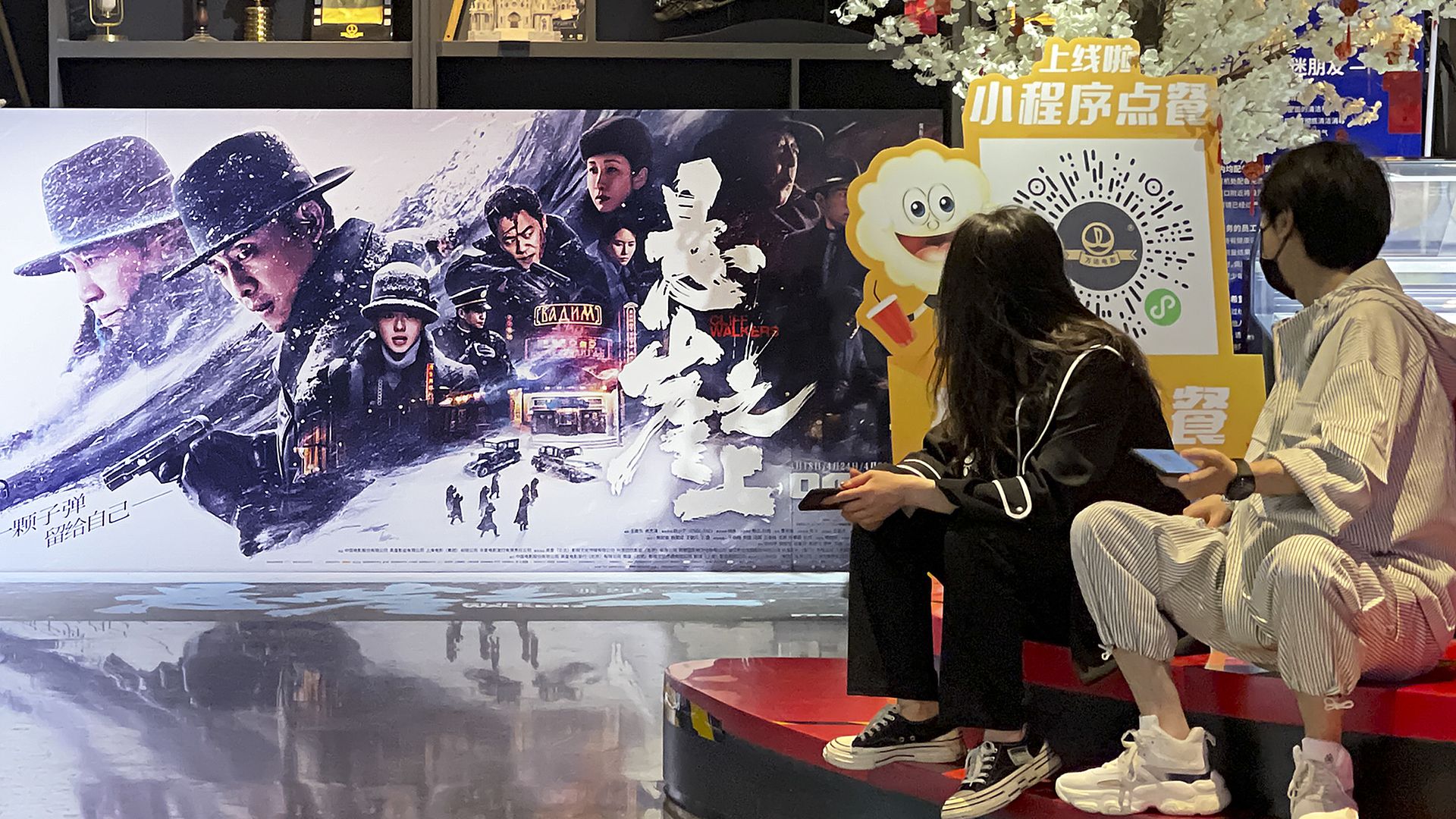 People watch a poster for film 'Cliff Walkers' at a cinema on the fourth day of the May Day holiday on May 4, 2021 in Beijing, China
