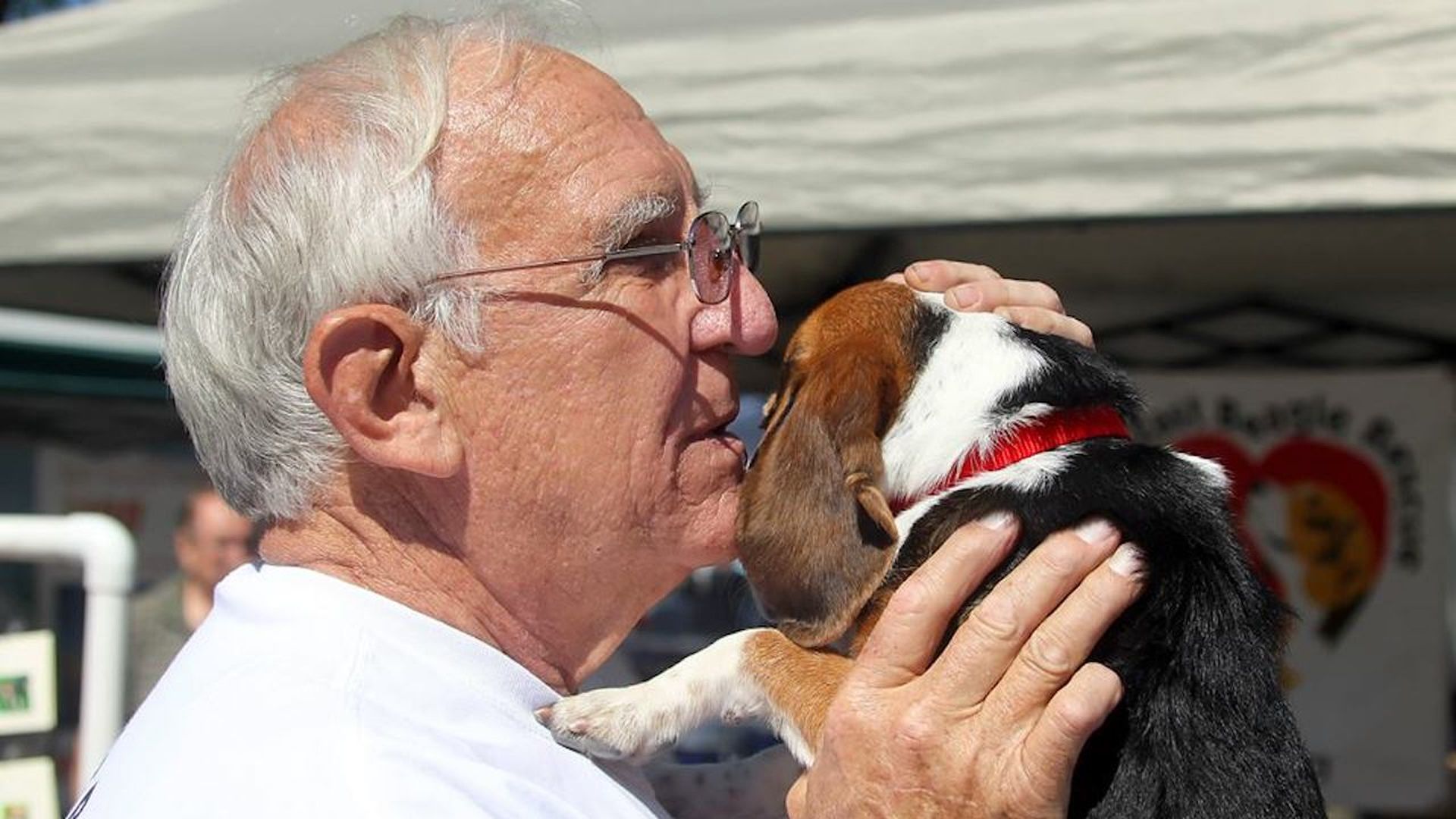 A man holding a beagle and whispering into its ear