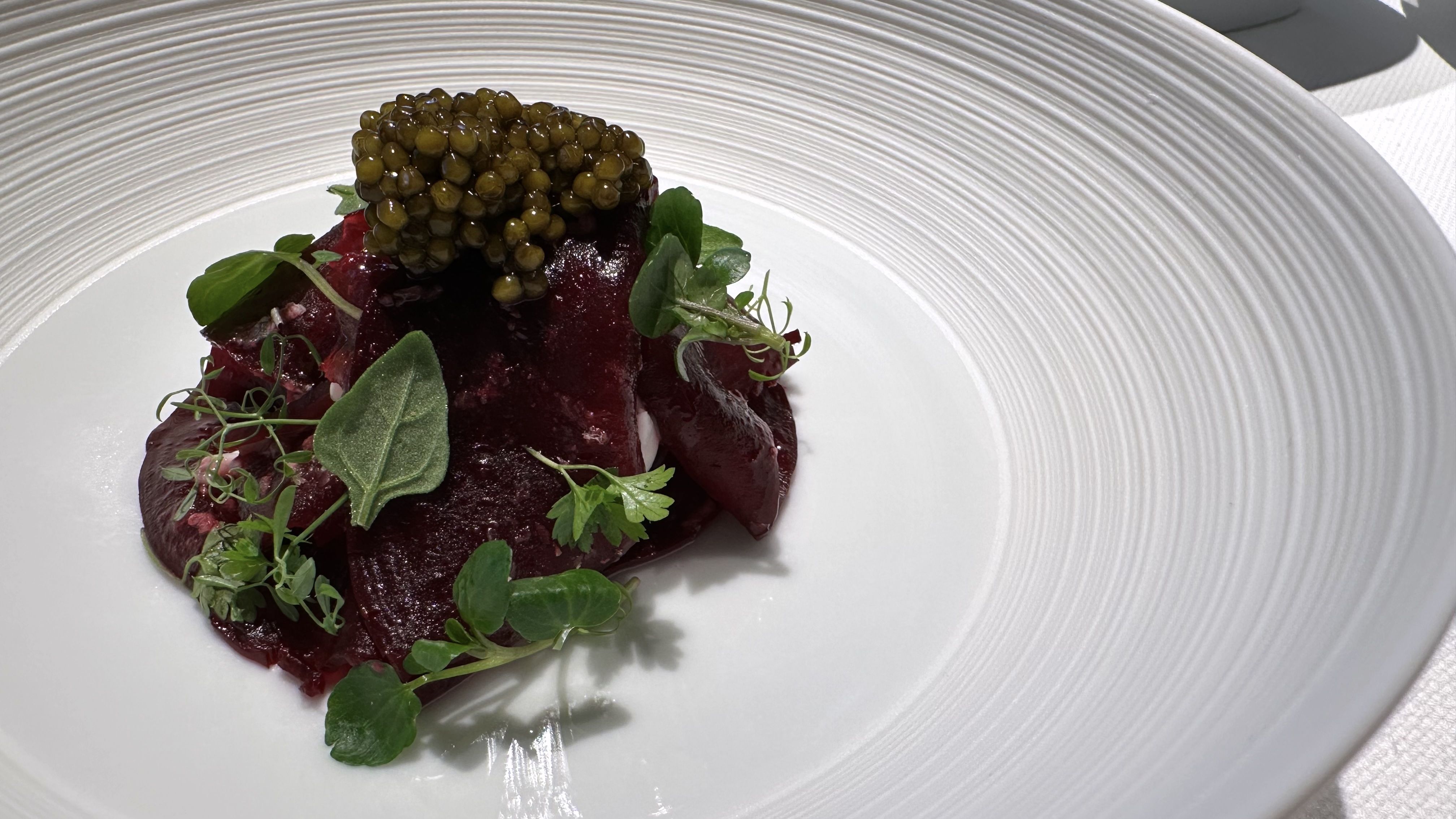 A beet salad sits on a white dish.