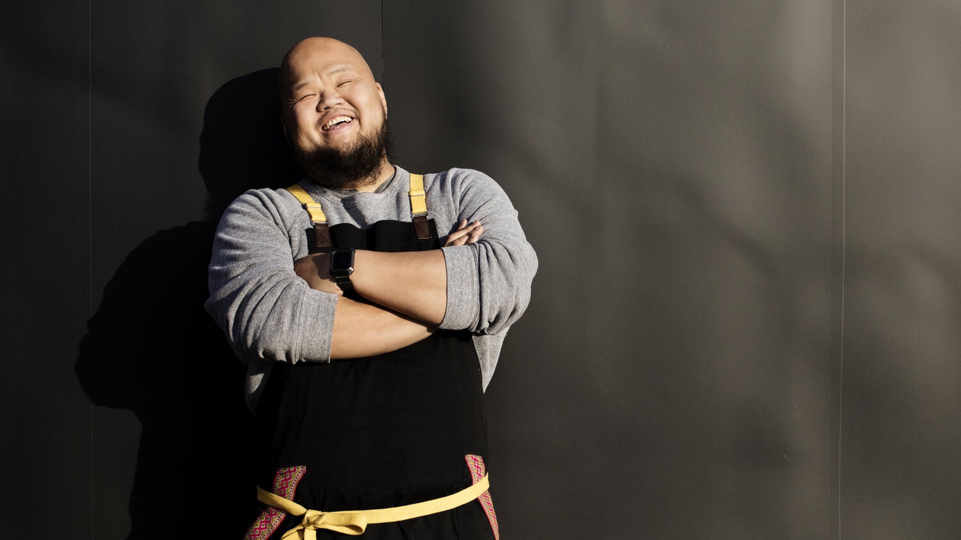 A photograph of chef Yia Vang smiling with his arms crossed.