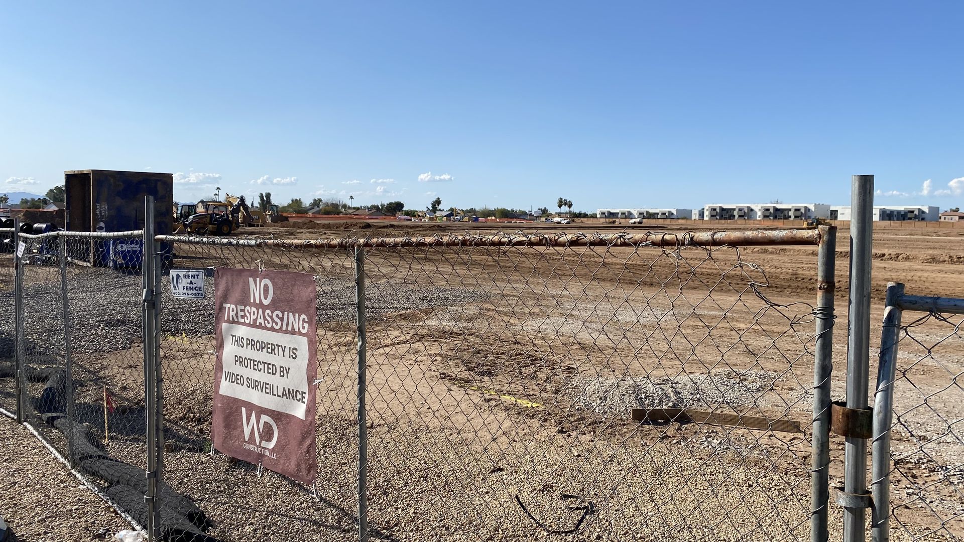 A fence with a no trespassing sign in front of a construction site.