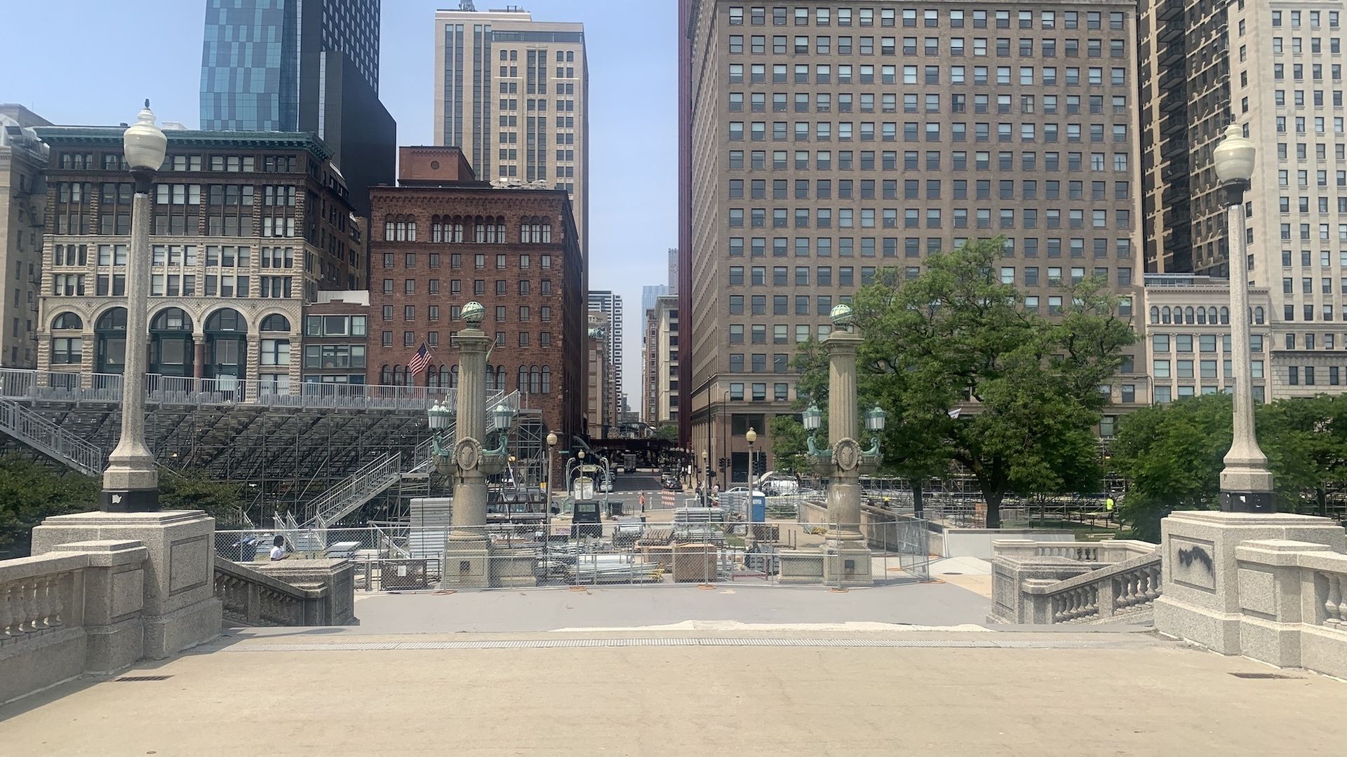 Concrete lamp posts, gray and brown buildings, bleachers, and construction materials at the Van Buren bridge looking west, for the set-up of the NASCAR street race.