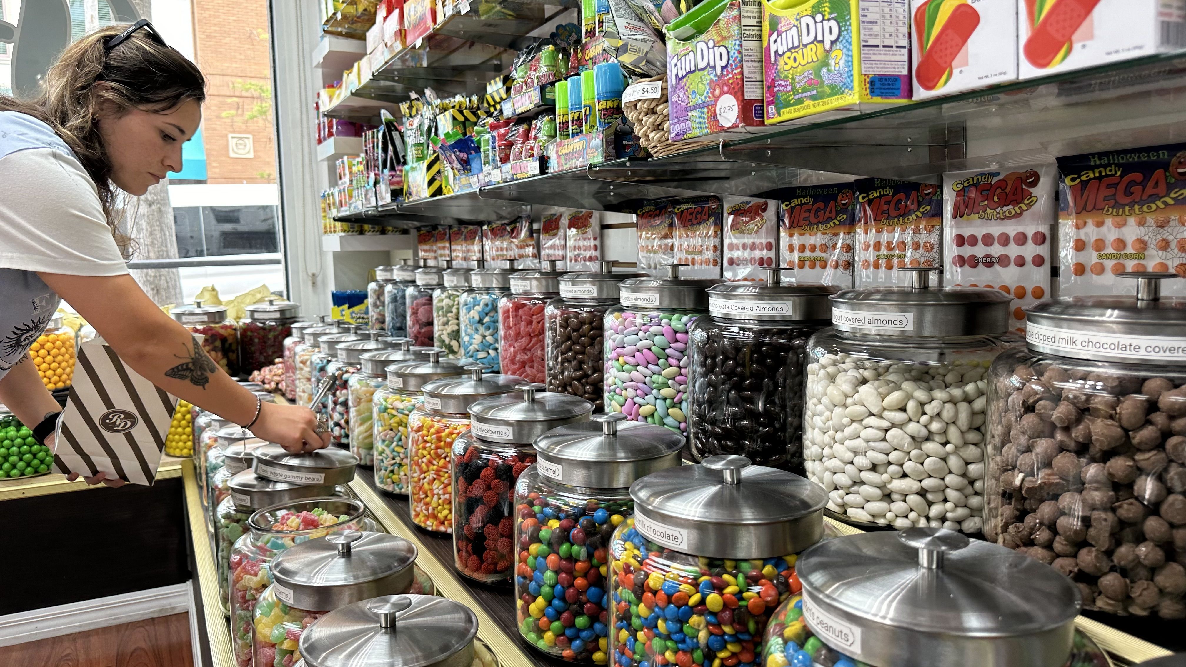A woman gets candy from rows of jars