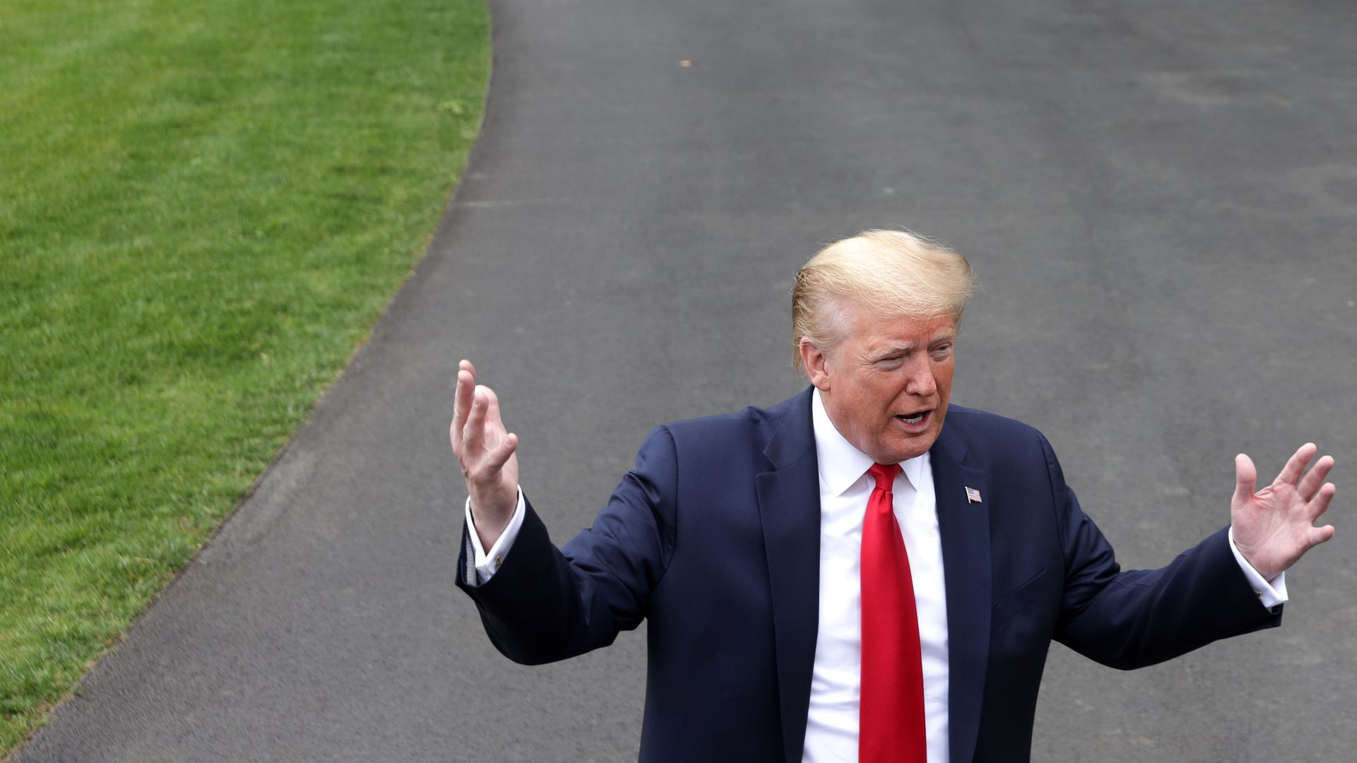 In this image, Trump stands in a suit in the White House driveway.