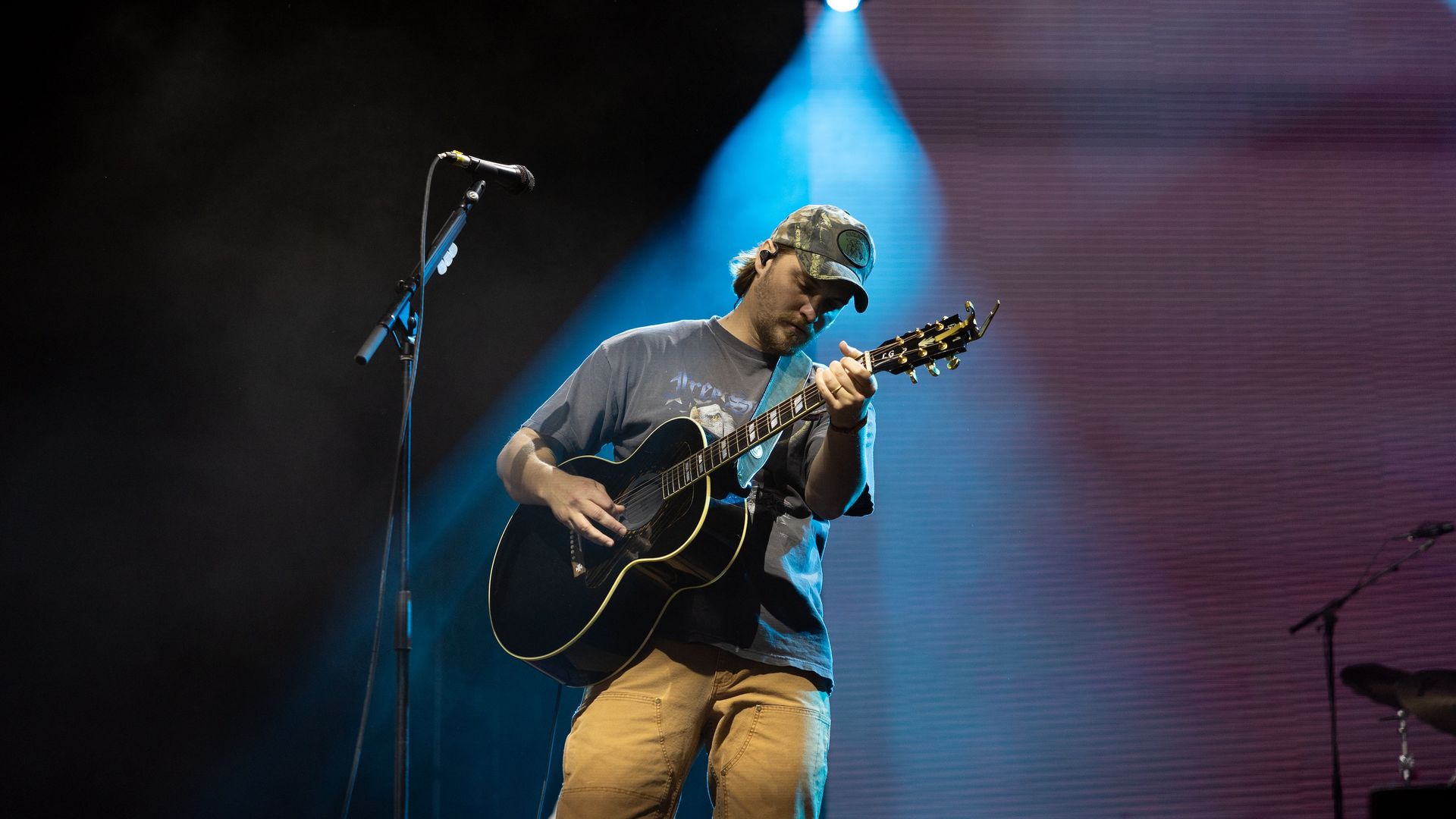 Actor/musician Luke Grimes performs on stage with his acoustic guitar. 
