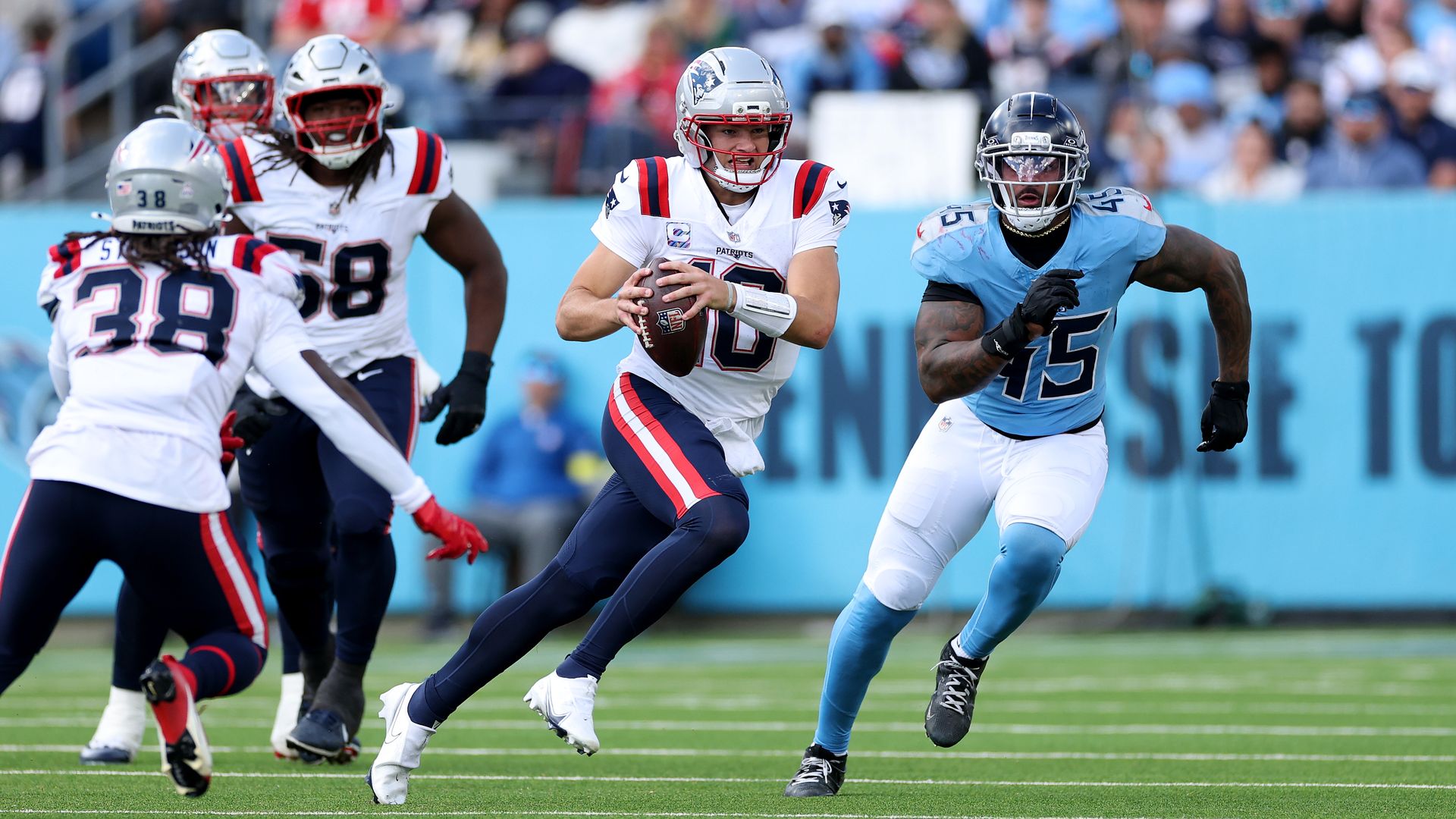 Drake May runs with the football  while a Tennessee Titans defender pursues him.