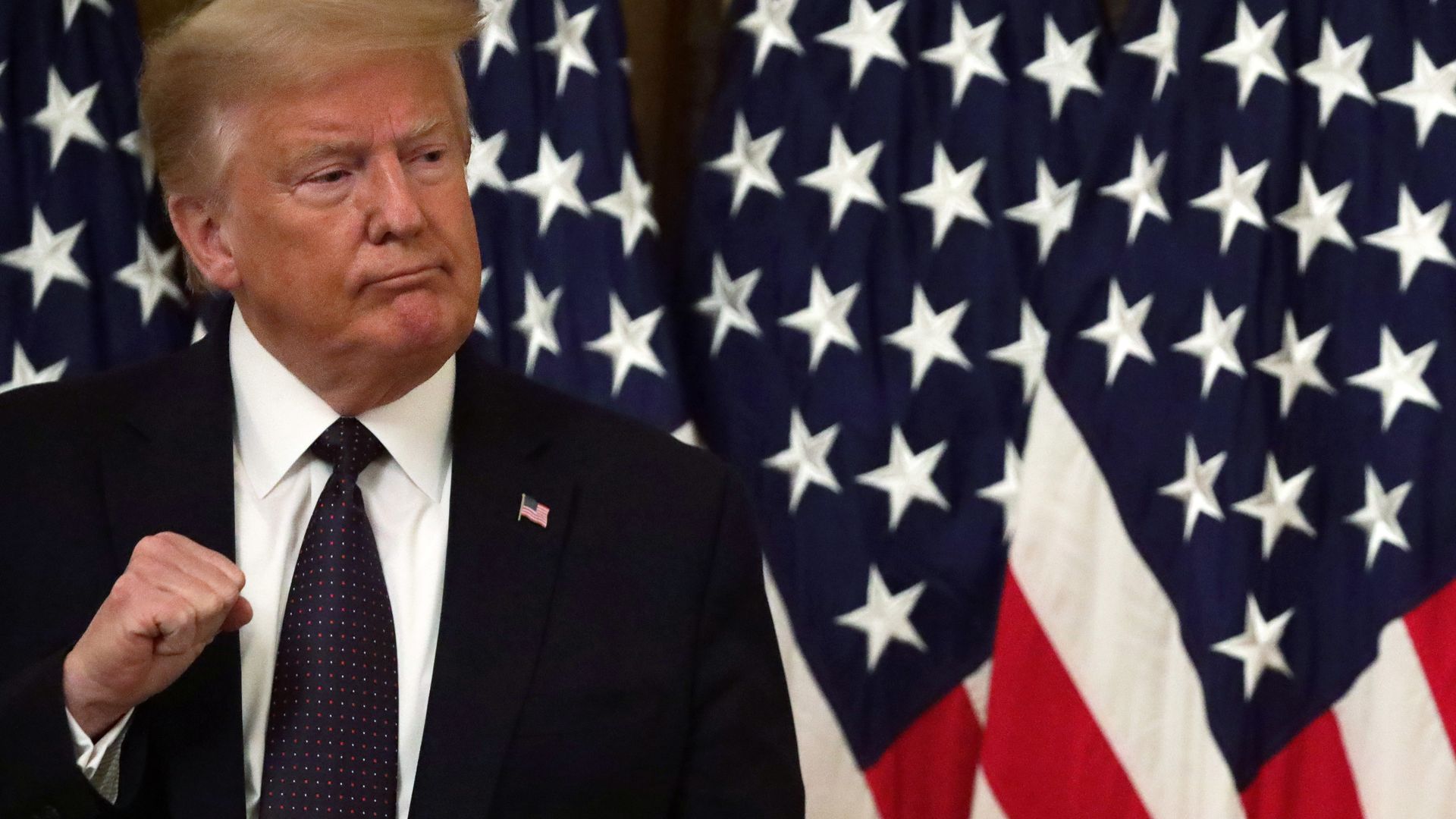 President Trump stands in front of American flags