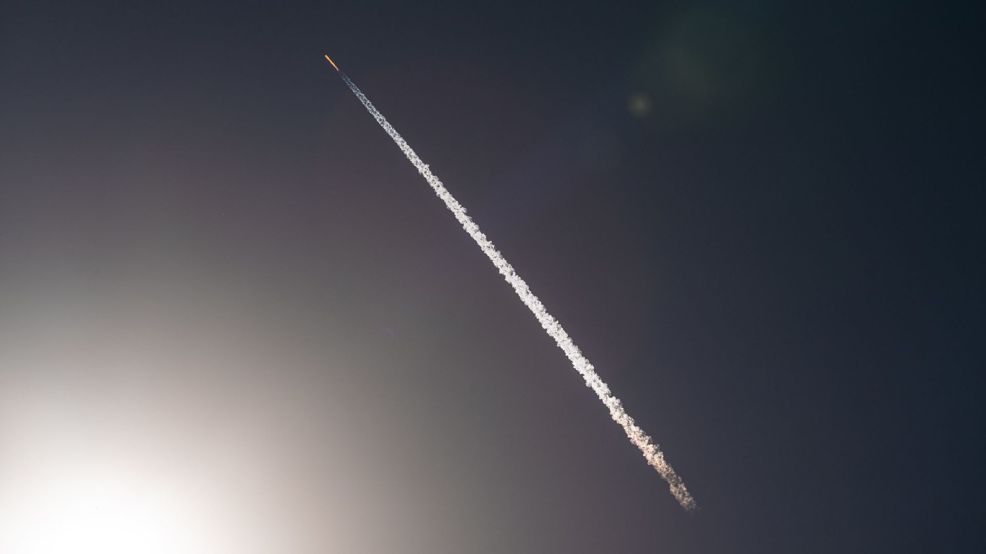 A Falcon 9 rocket launch illuminated by the Sun.