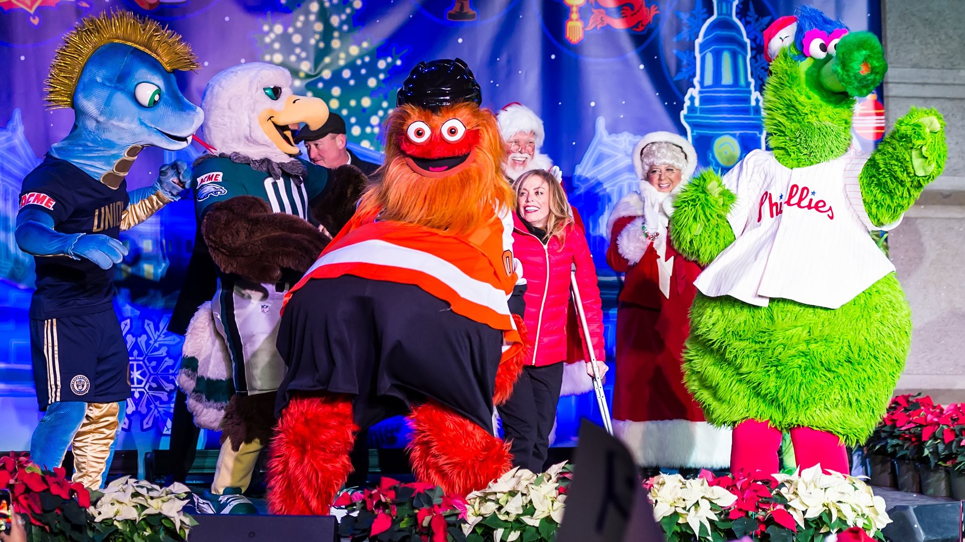 Philadelphia mascots Phang, Swoop, Gritty and Phanatic, alongside Santa Claus and Mrs. Claus stand on stage during the city's 2018 Holiday Tree Lighting.