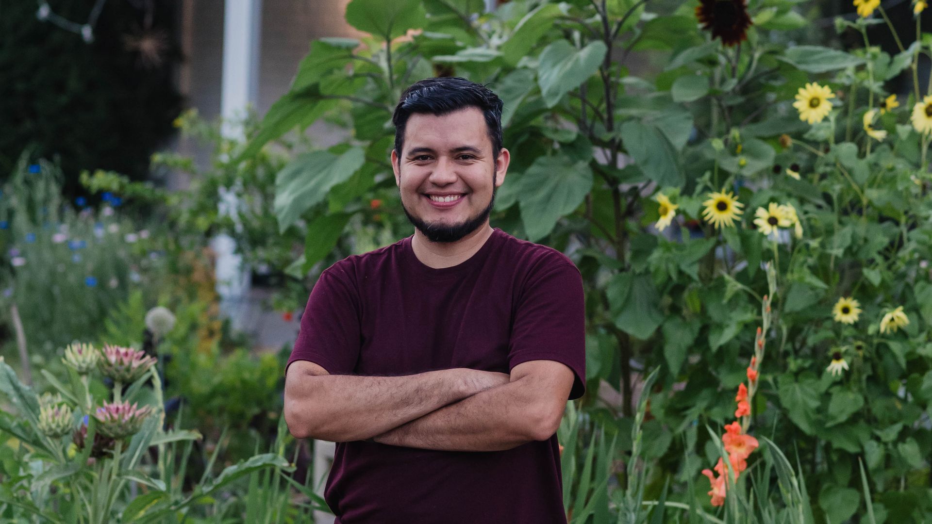man in a red shirt standing in his backyard garden