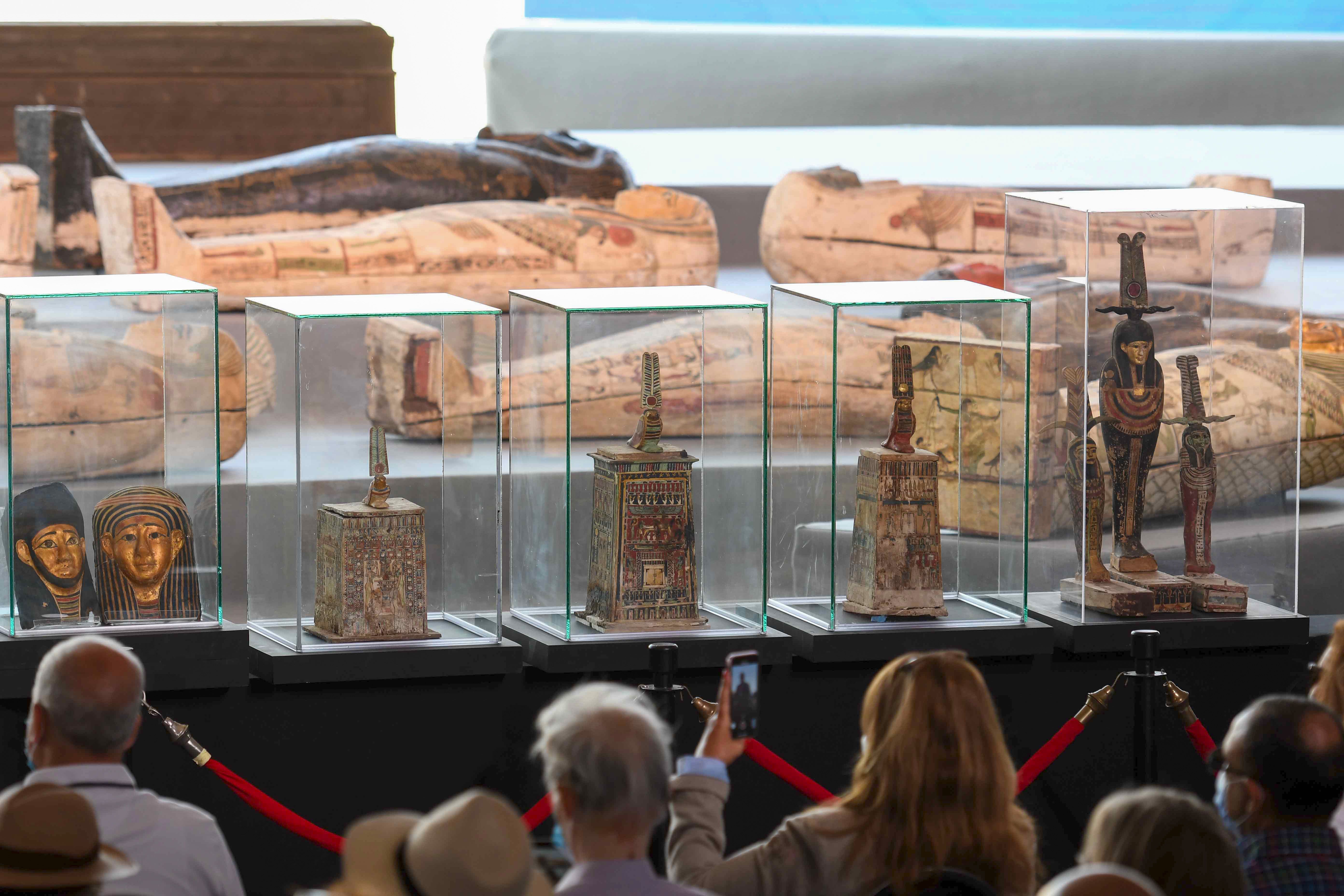 A picture shows statues and funerary masks on display during the unveiling of an ancient treasure trove of more than a 100 intact sarcophagi, at the Saqqara necropolis 