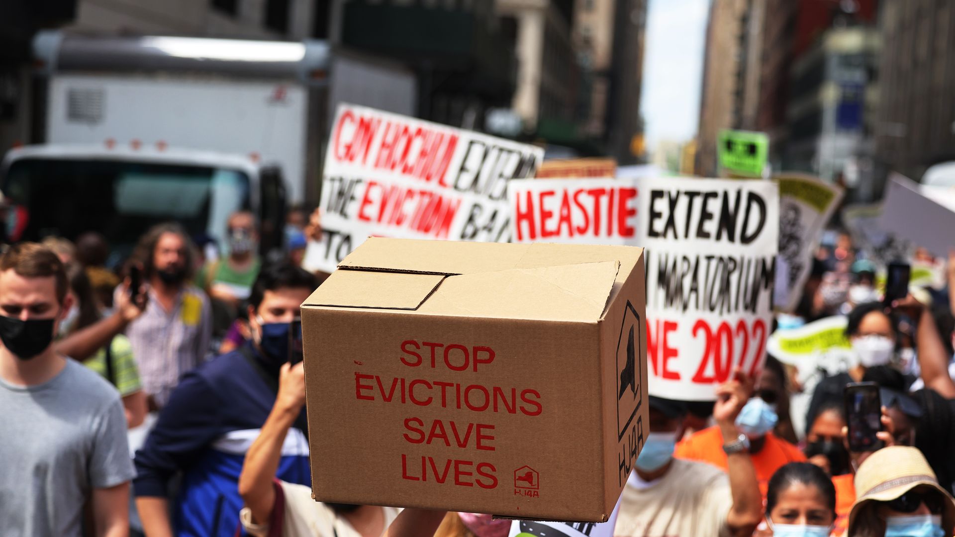 Picture of a protest and people are holding a box that says "stop evictions save lives"