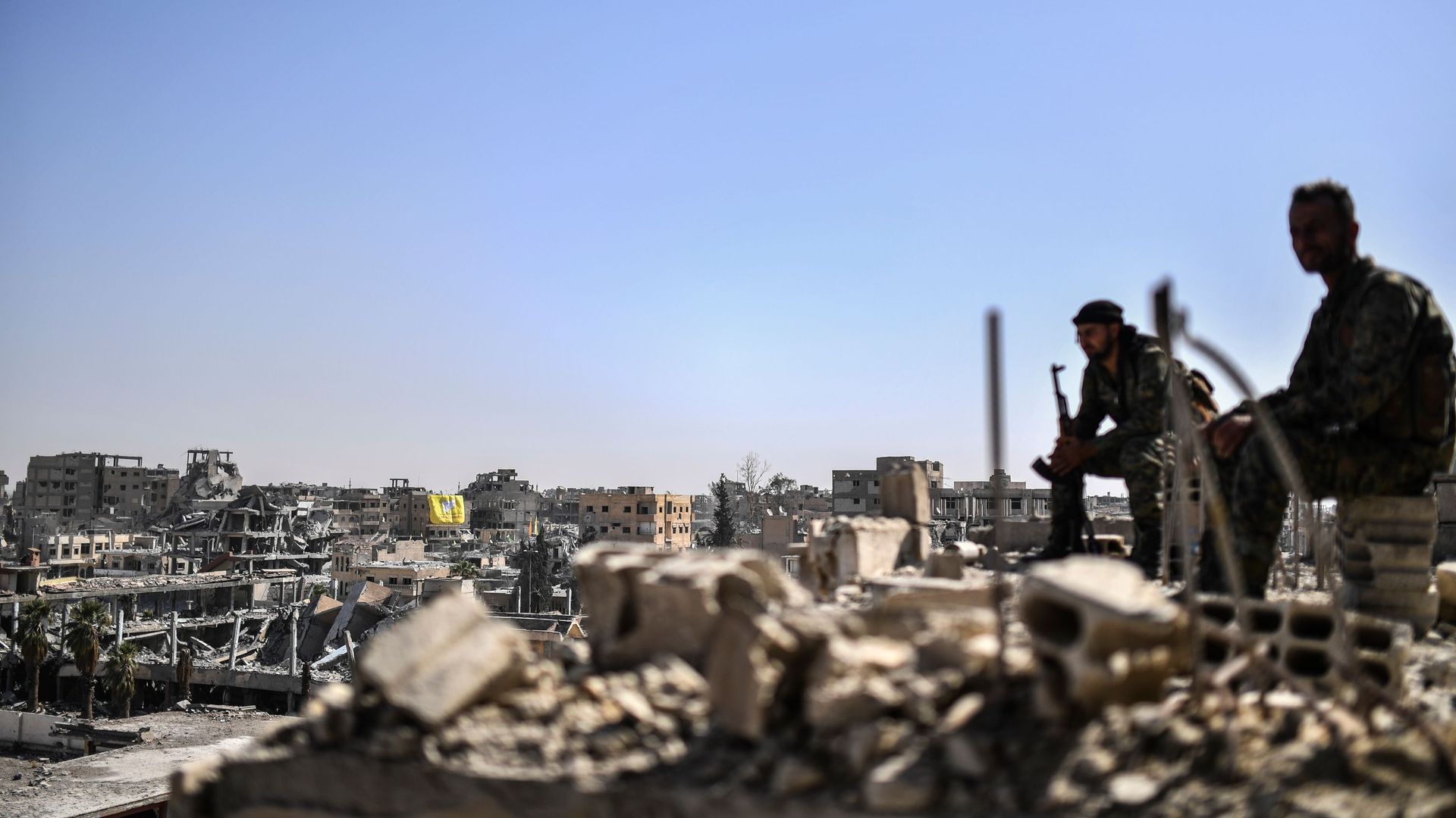 Fighters of the Syrian Democratic Forces stand guard on a rooftop in Raqqa. 